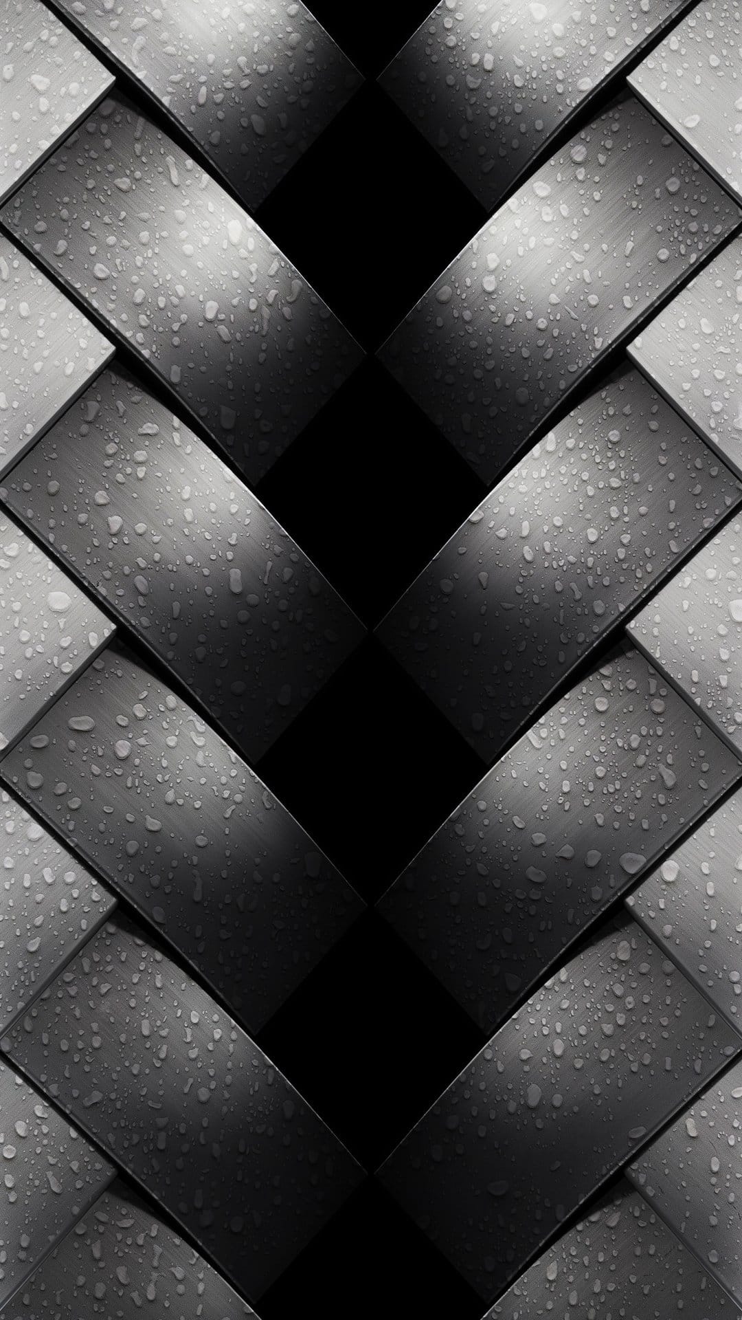 Tiny water droplets cling to a dark interlaced metallic surface with sharp highlights and deep shadows.