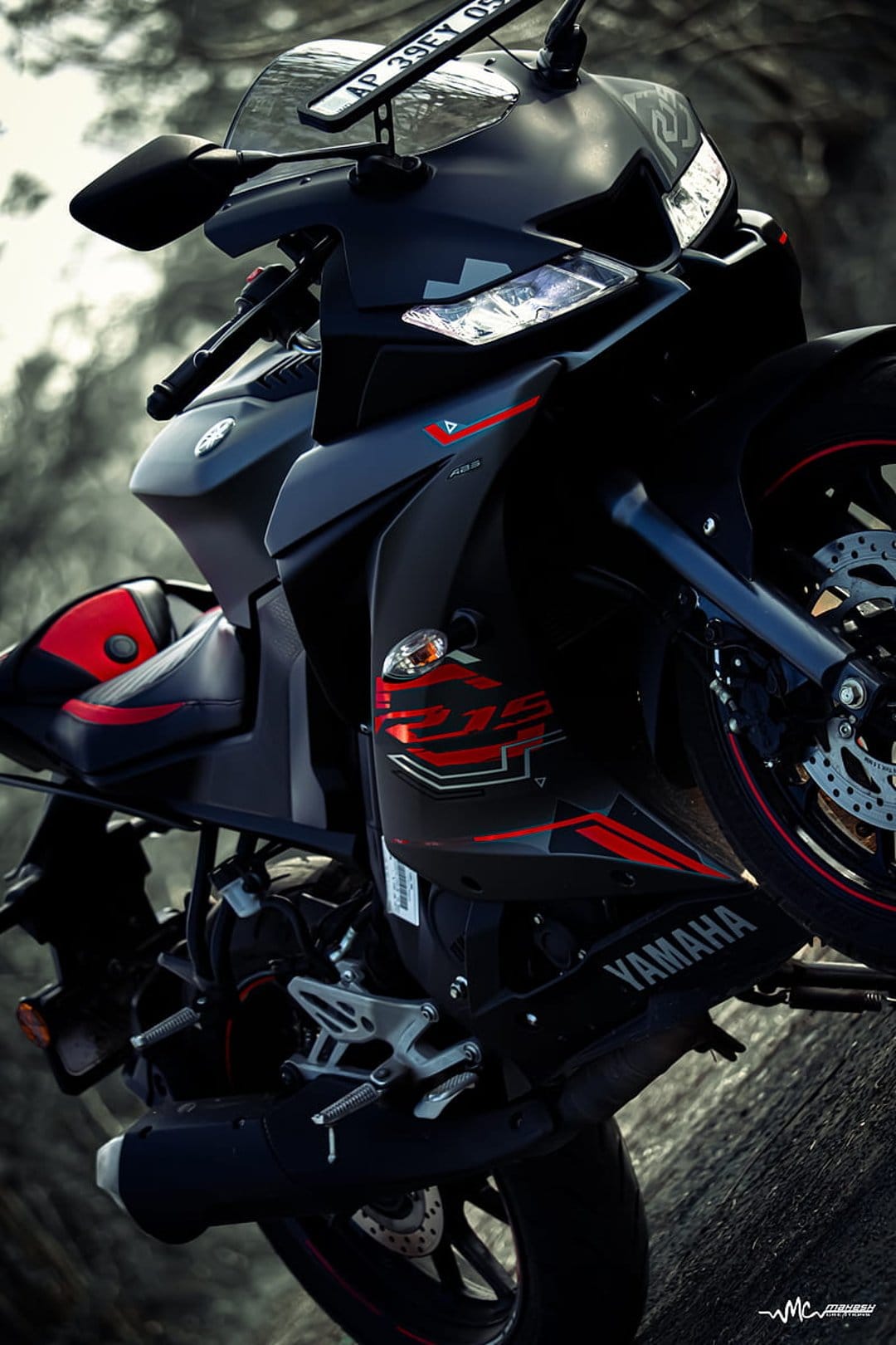 Black Yamaha R15 sportbike with glowing dual LED headlights and sharp fairings featuring red accent decals.