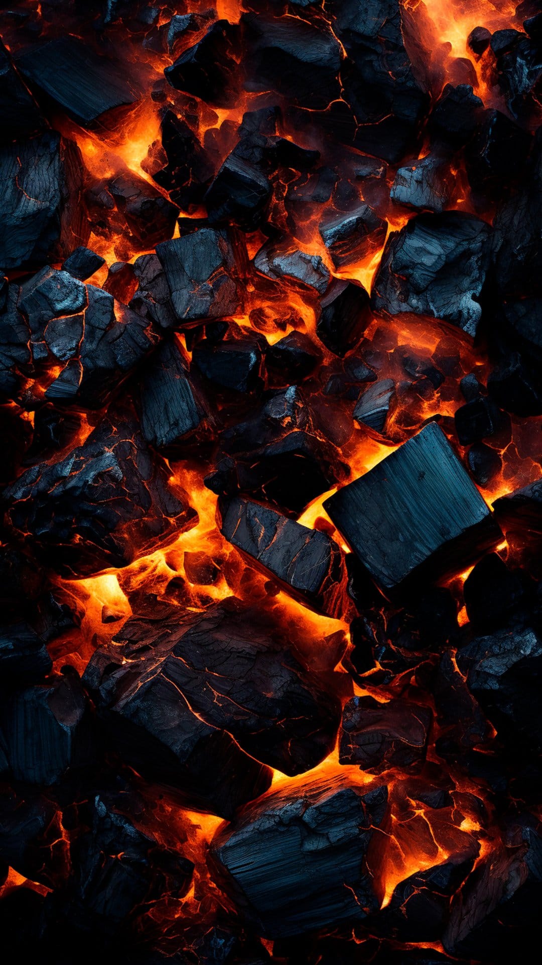 Red-hot embers glow intensely between jagged pieces of black charcoal in a macro high-angle vertical shot.