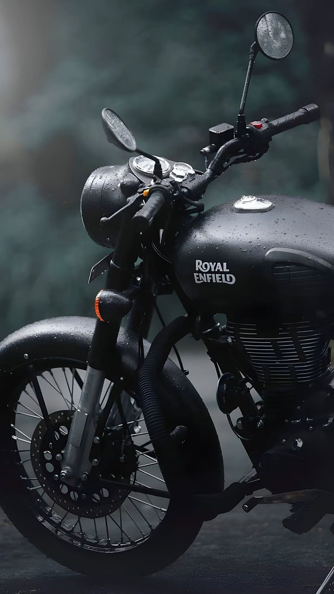 Royal Enfield motorcycle fuel tank features glistening water droplets on matte black paint in the rain.