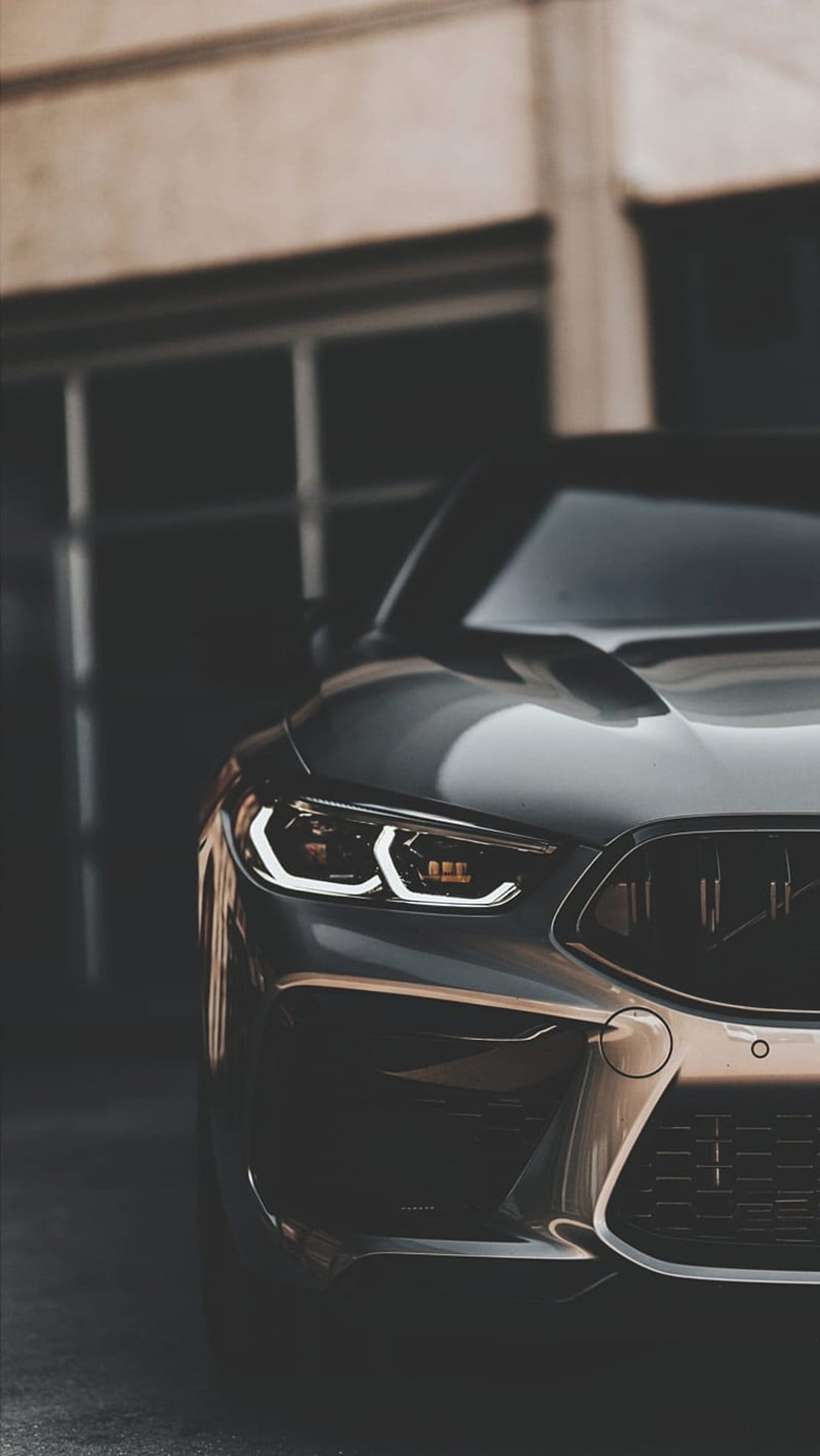Sleek grey car headlight features a glowing C-shaped LED light strip against polished metallic bodywork panels.