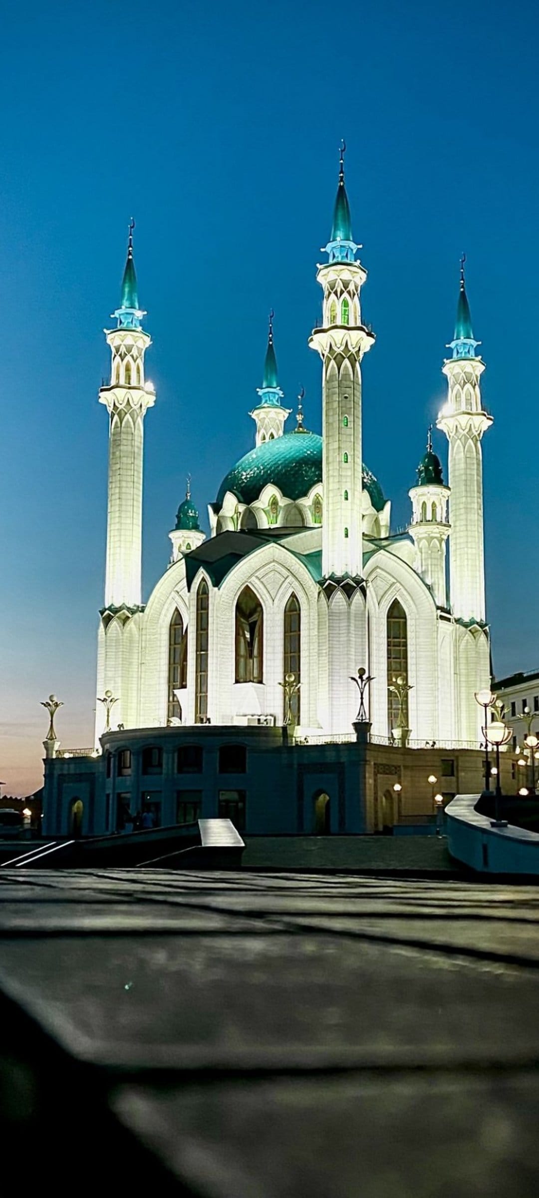 Kul Sharif Mosque features glowing white walls and turquoise domes against a deep blue evening sky in Kazan.