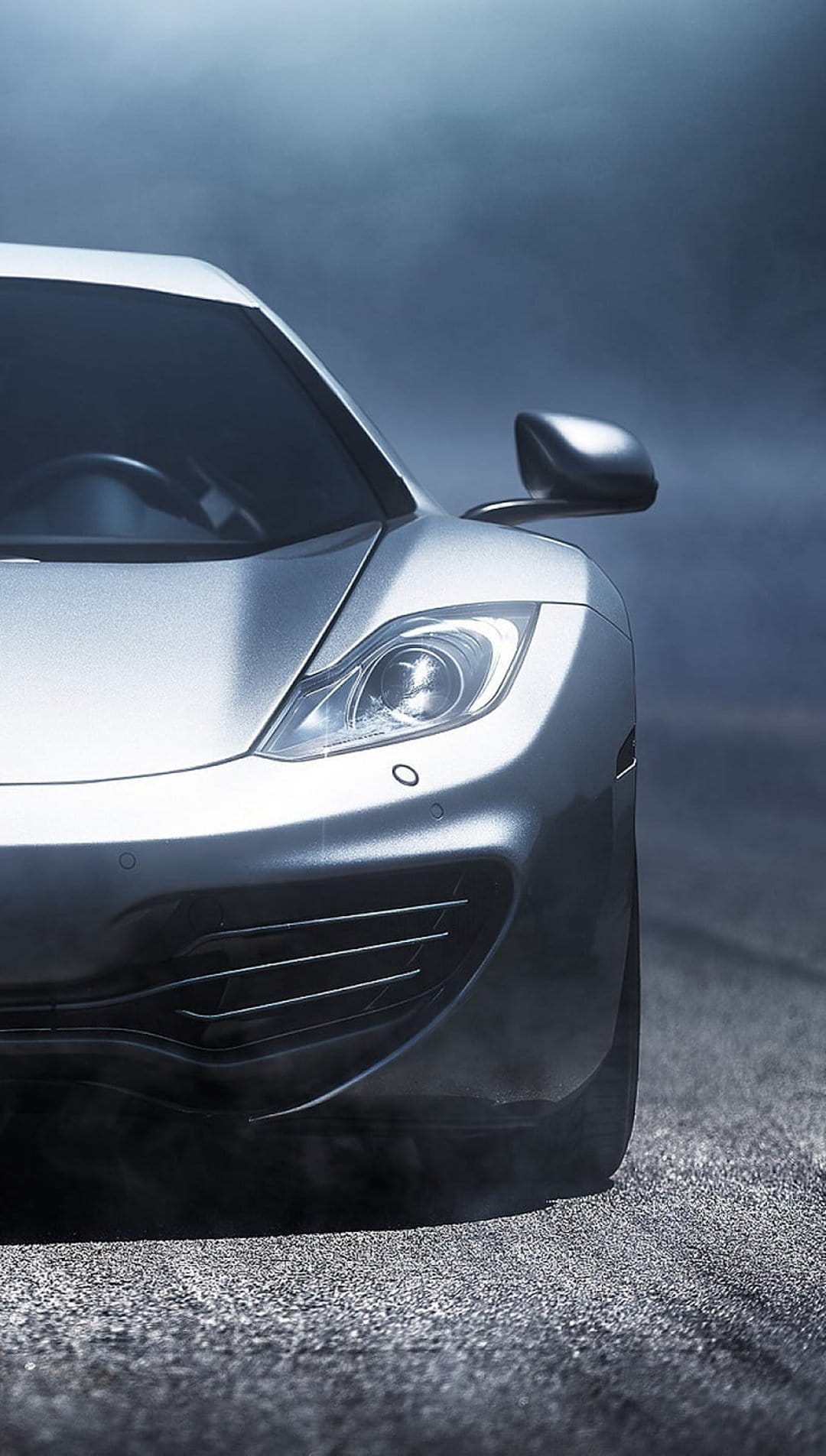 Silver sports car front profile with glowing headlights and side mirrors visible through thick grey smoke.