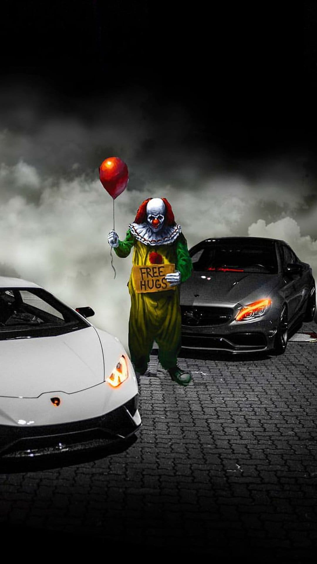 Scary clown holding a red balloon and free hugs sign between a white Lamborghini and a dark Mercedes-Benz.