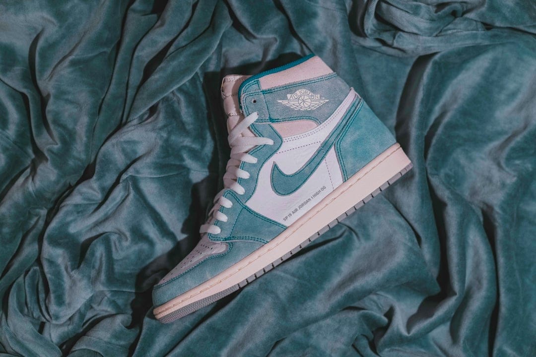 Air Jordan 1 High OG teal and white sneakers showing suede textures, the Nike Swoosh, and a leather high-top frame.