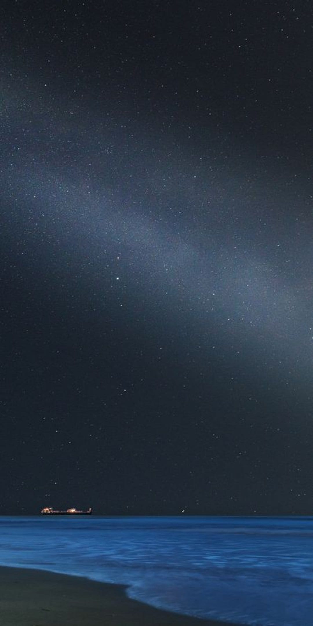 Small illuminated boat floating on a calm dark ocean under a starry sky and a visible Milky Way galaxy.