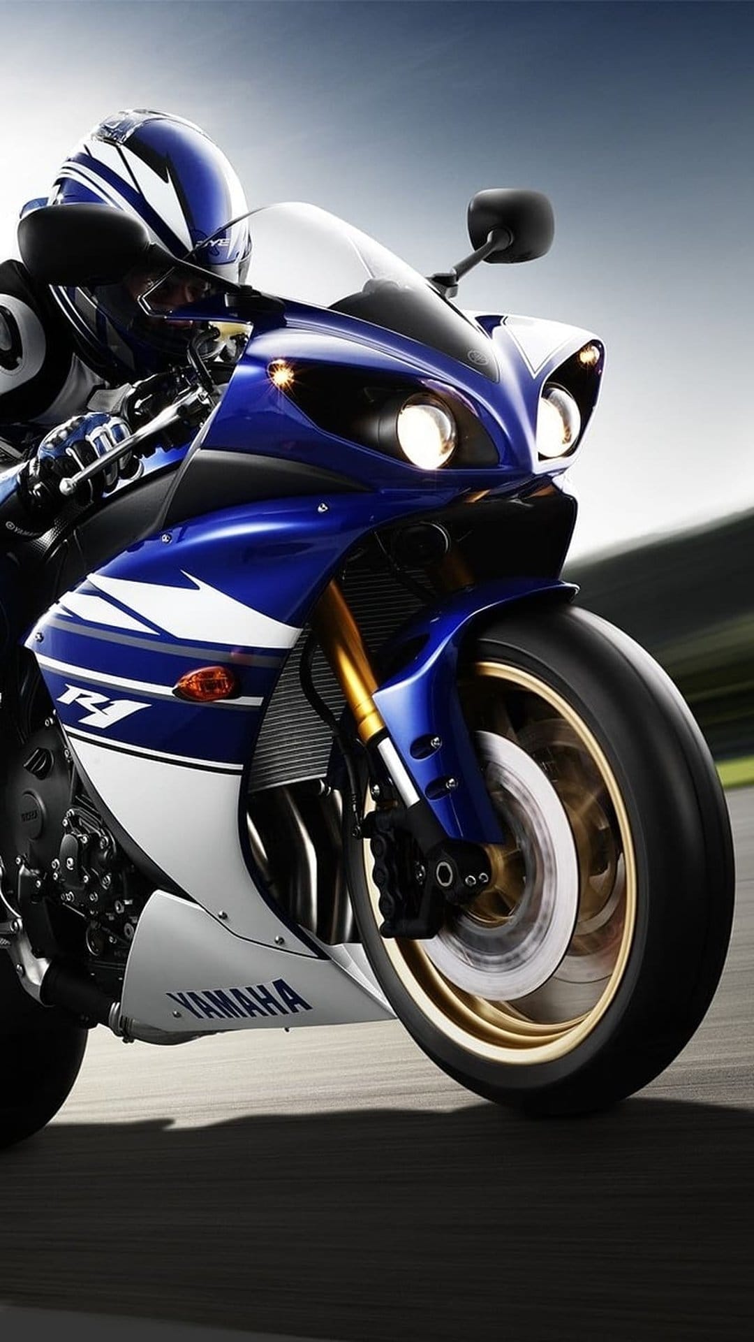 Yamaha R1 motorcycle features blue fairings and gold suspension while speeding with realistic motion blur.