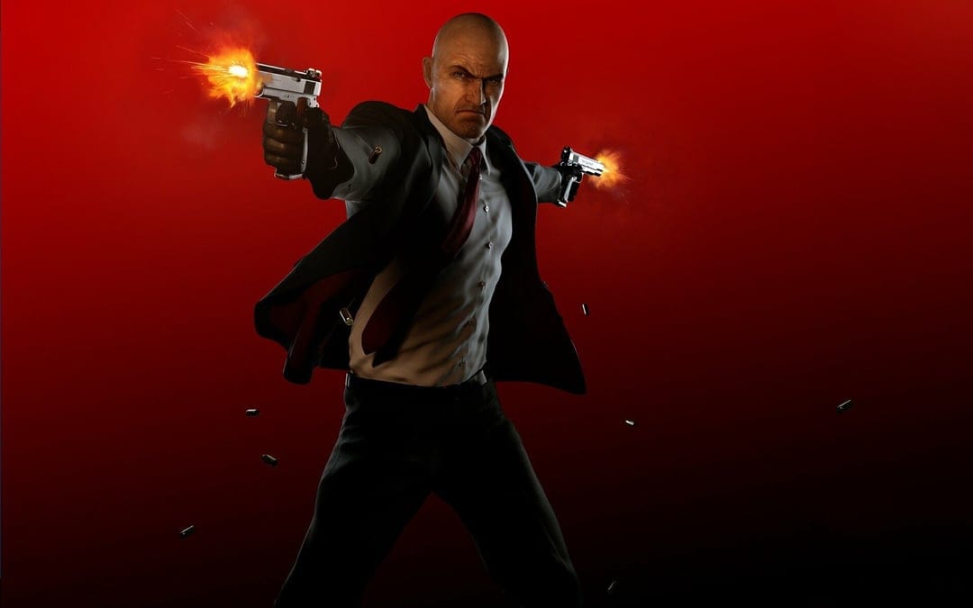 Agent 47 fires dual silver pistols with muzzle flashes against a red backdrop while wearing a dark suit.