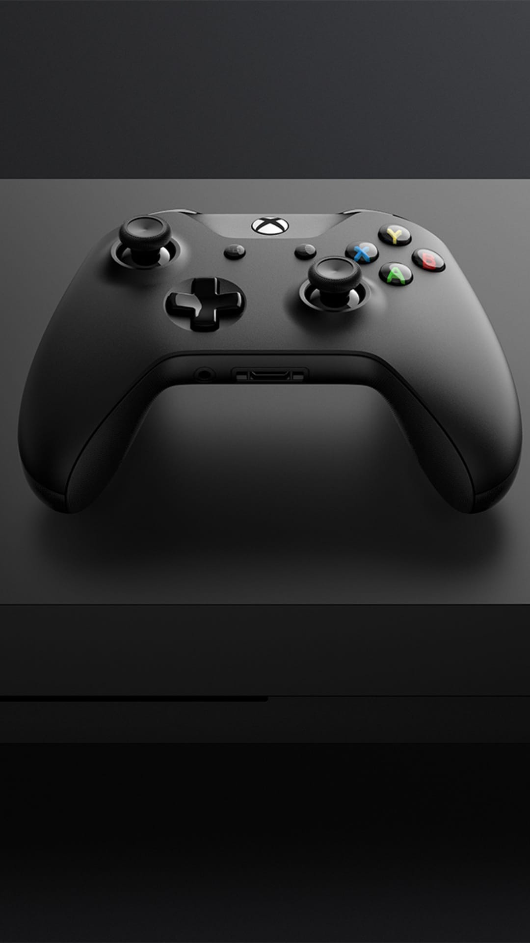Xbox wireless controller in matte black illuminated from above on a dark surface with soft blur background.