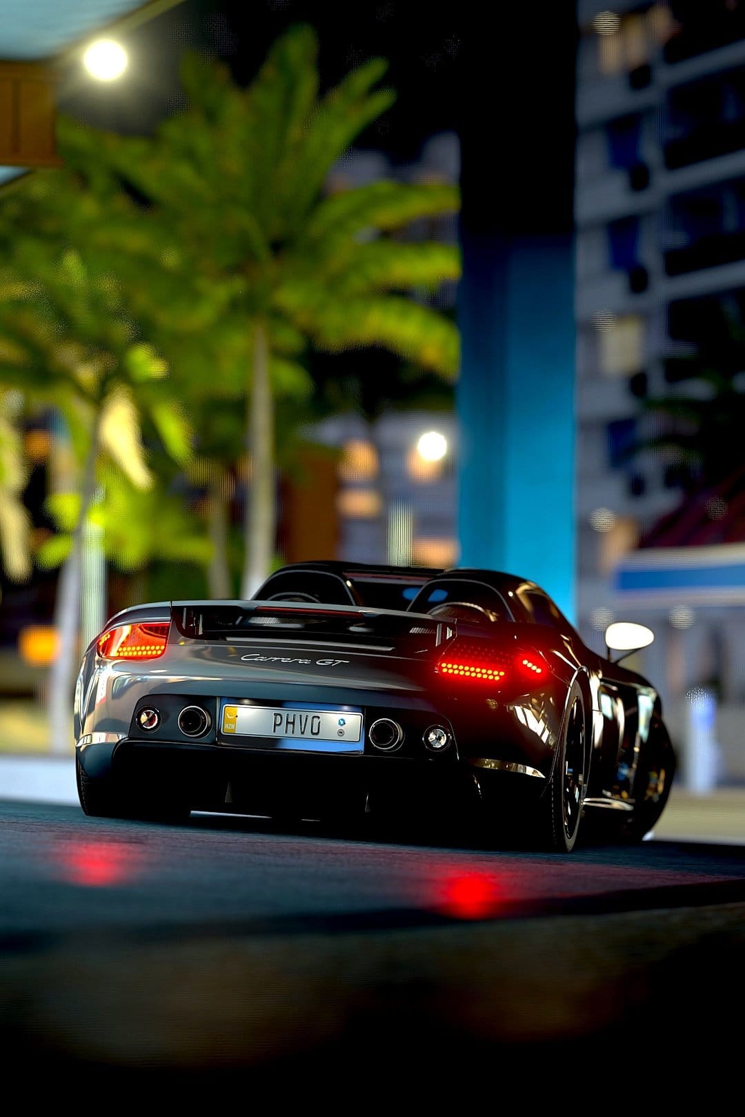 Black Porsche Carrera GT seen from behind with glowing red taillights against a blurred night city background.