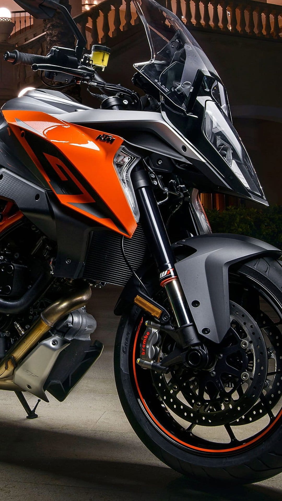 KTM adventure motorcycle front fairing featuring orange panels, dual headlights, and exposed front suspension.