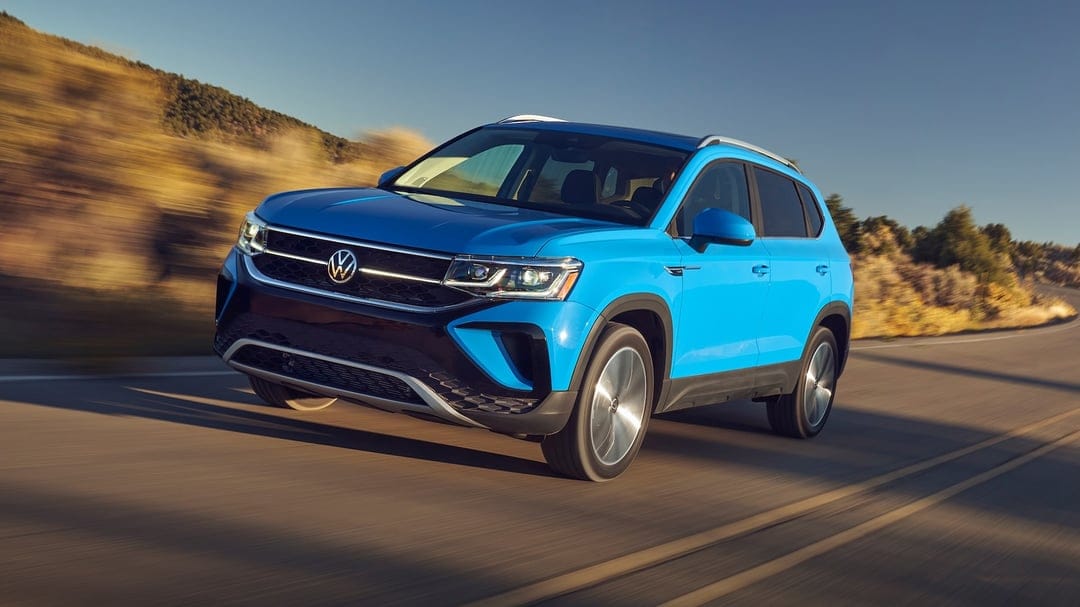 Blue Volkswagen SUV driving on a highway with motion blur against a golden hour desert landscape.