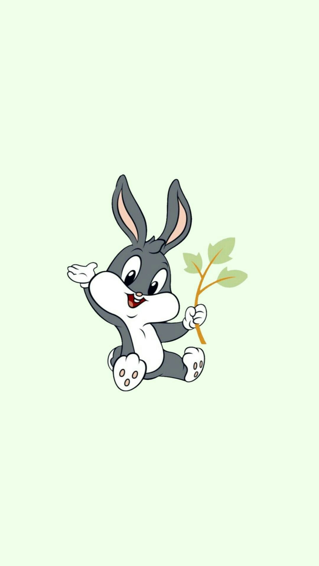 Baby Bugs Bunny sits holding a three-leaf green sprig against a solid pastel mint green background.