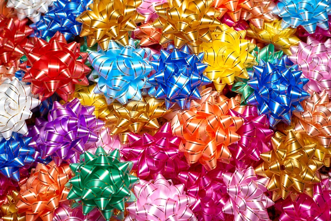 Red, gold, and blue star-shaped metallic gift bows clustered together with reflective surfaces and sharp edges.