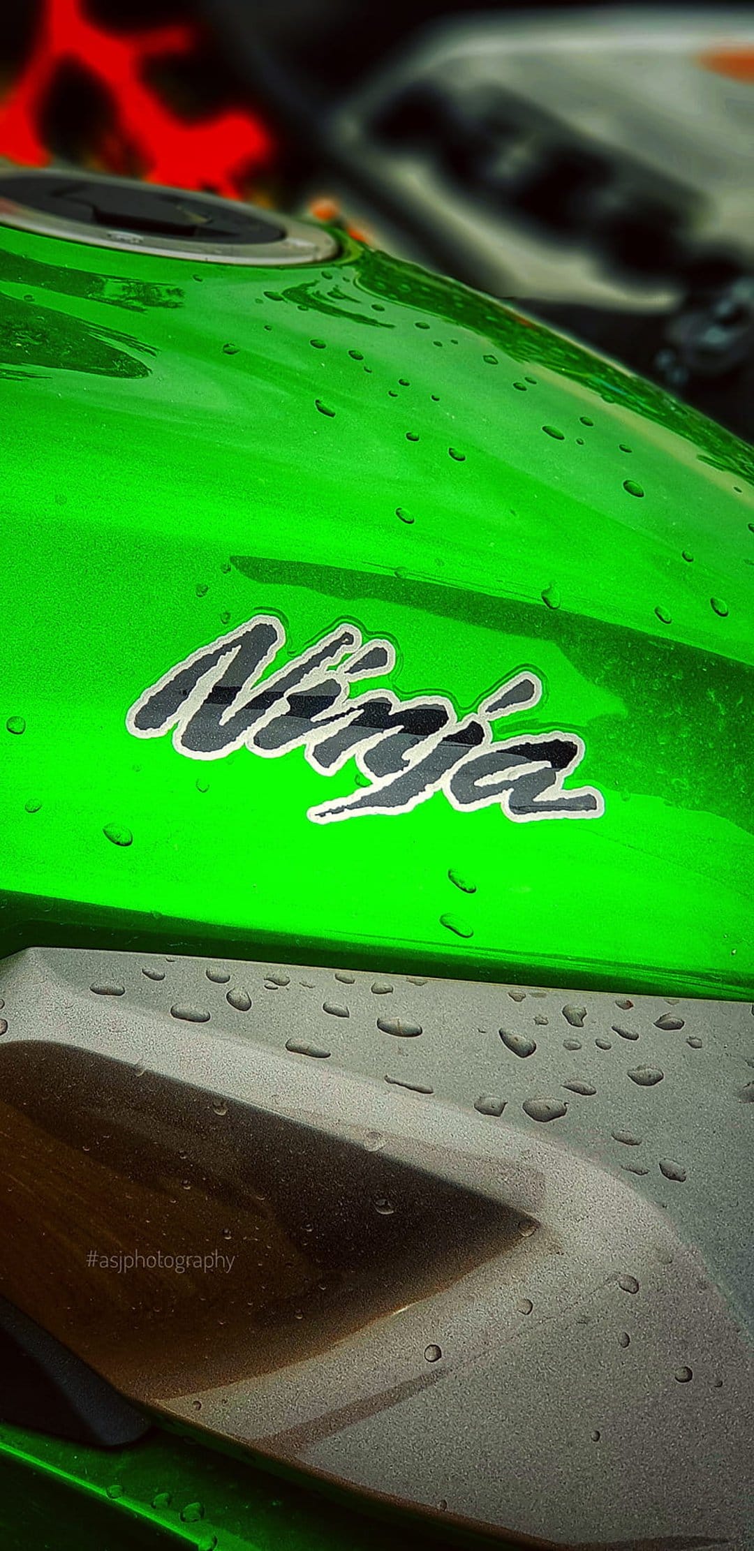 Kawasaki Ninja motorcycle fuel tank in lime green with translucent water droplets and a blurred background.