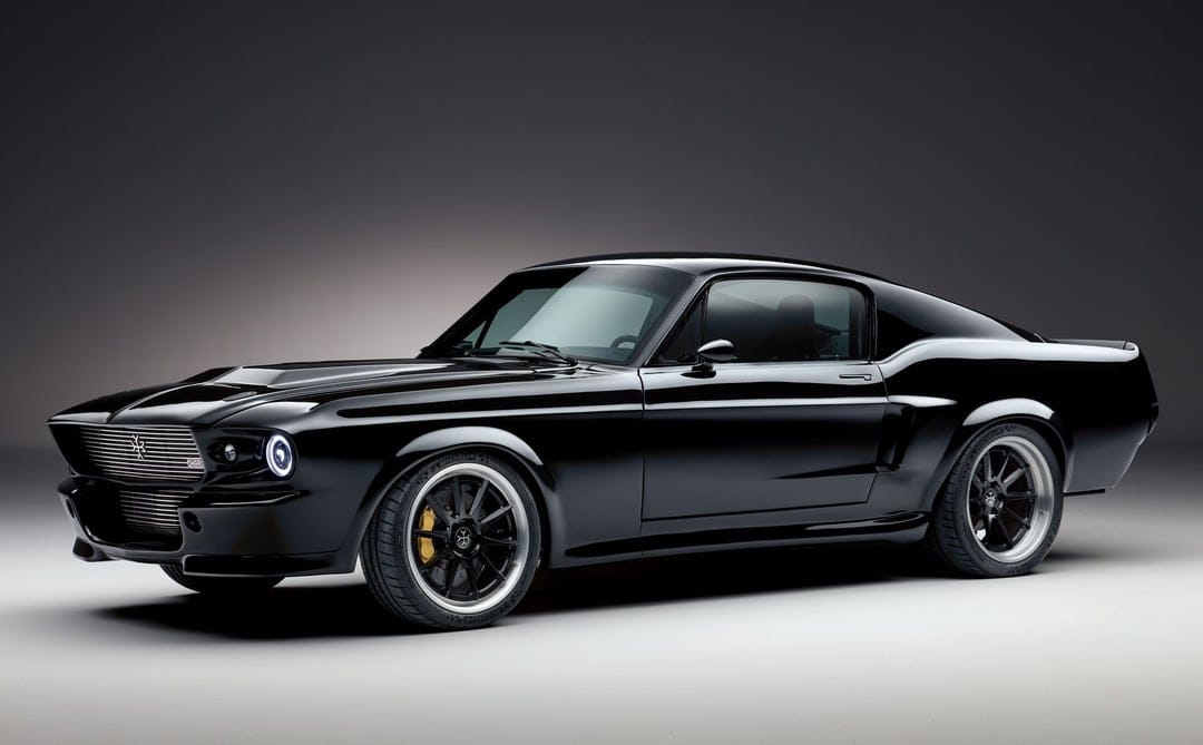 Black electric classic muscle car with glowing LED headlights in a minimalist grey studio environment.