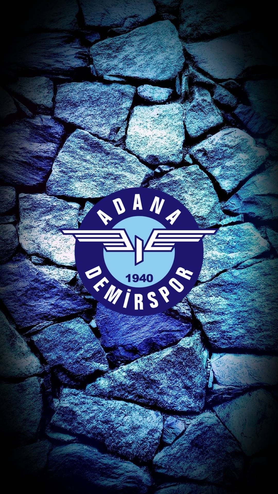 Adana Demirspor club logo with the year 1940 displayed on a dark blue and grey textured masonry stone wall.
