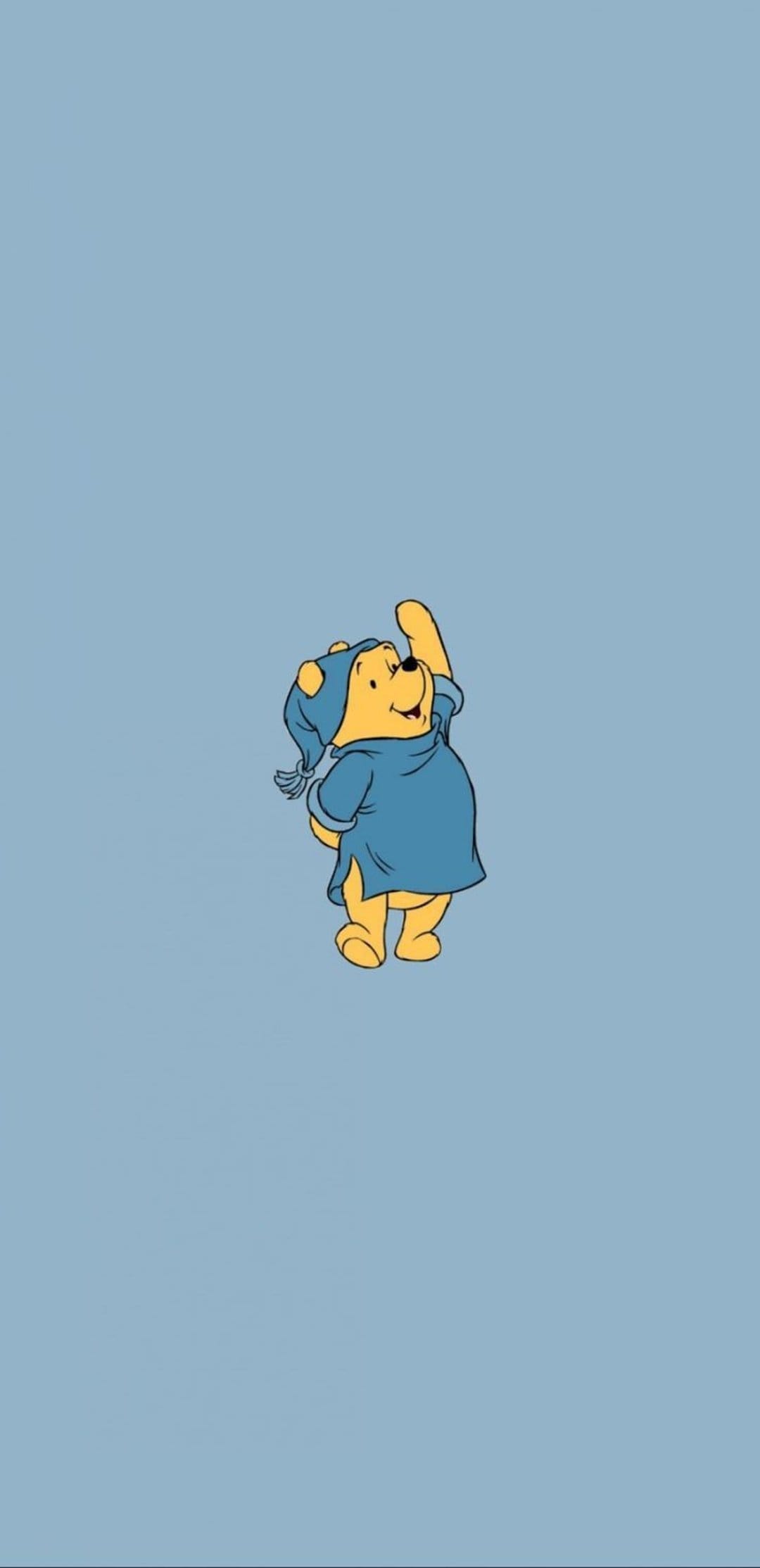 Winnie the Pooh wears a blue nightshirt and matching cap while waving against a light blue background.
