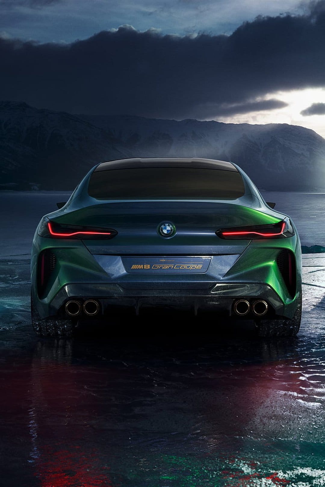BMW M8 Gran Coupe Concept rear showing red LED taillights, quad exhausts, and green paint against mountain peaks.