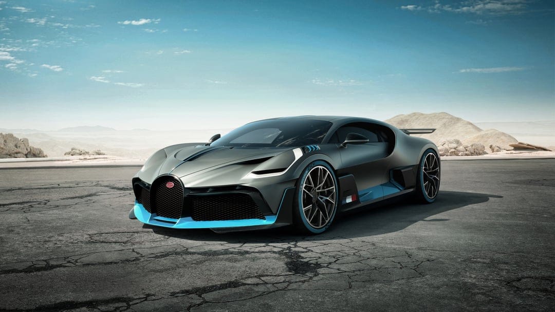 Bugatti Divo hypercar in matte gray with blue accents parked on a cracked road under a clear blue desert sky.