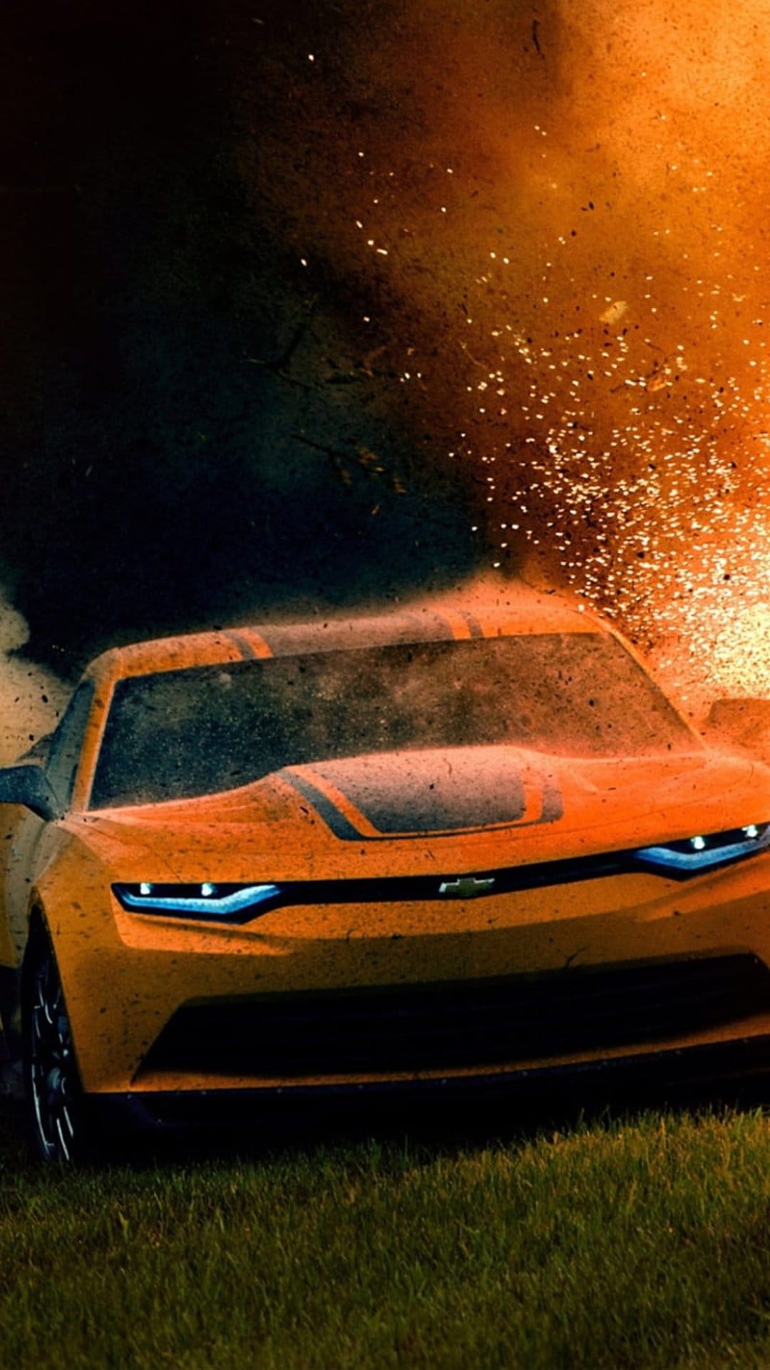 Yellow Chevrolet Camaro drives through a cloud of orange sparks and dark smoke during a cinematic explosion.