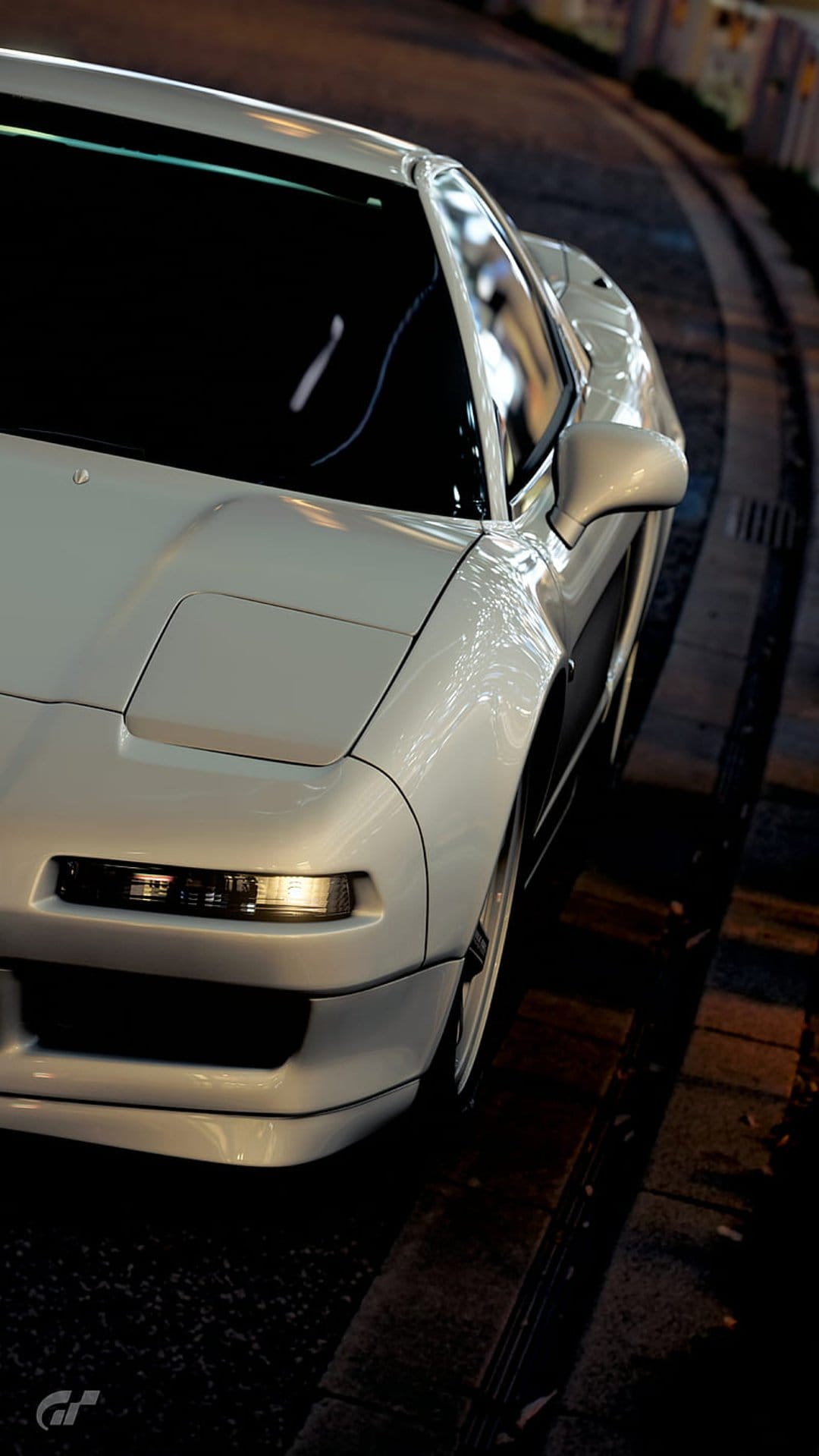 White Honda NSX with pop-up headlights on a curving dark city street at night with soft urban light reflections.