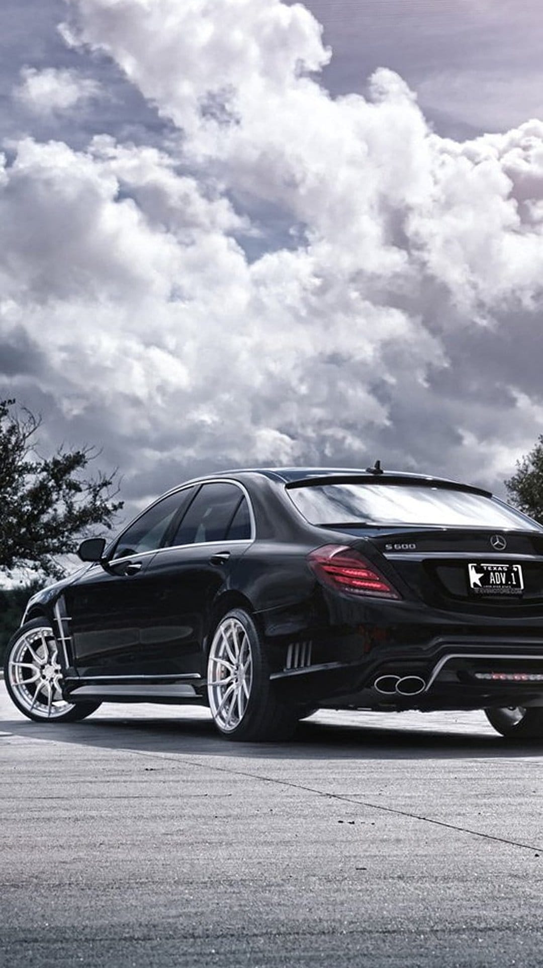 Black Mercedes S600 sedan with ADV.1 wheels parked on asphalt under a dramatic, cloudy Texas sky at dusk.