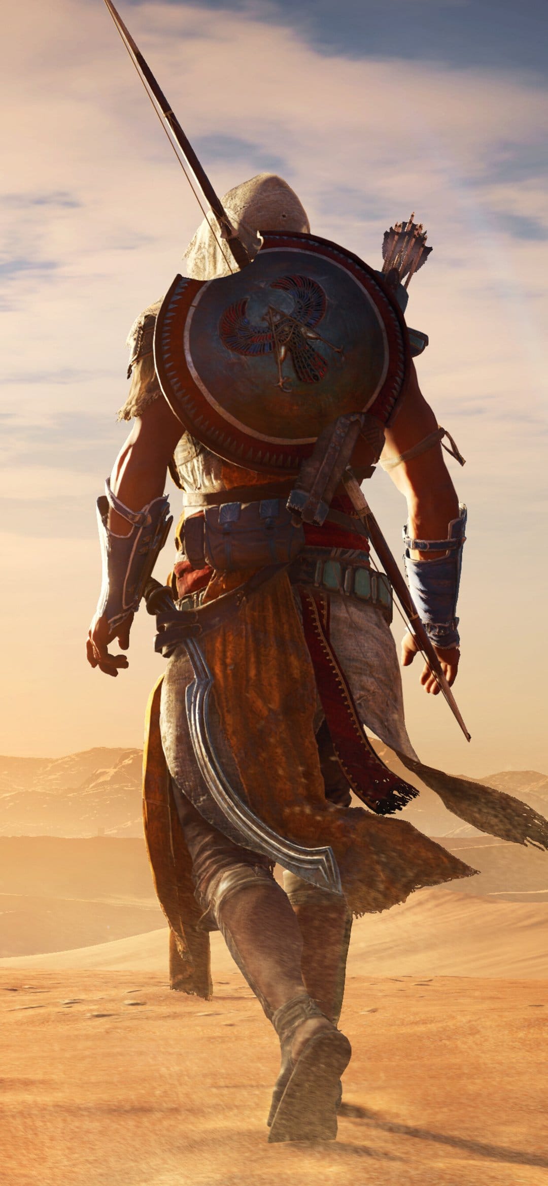 Bayek from Assassin's Creed Origins walking through golden desert dunes with a shield and bow on his back.