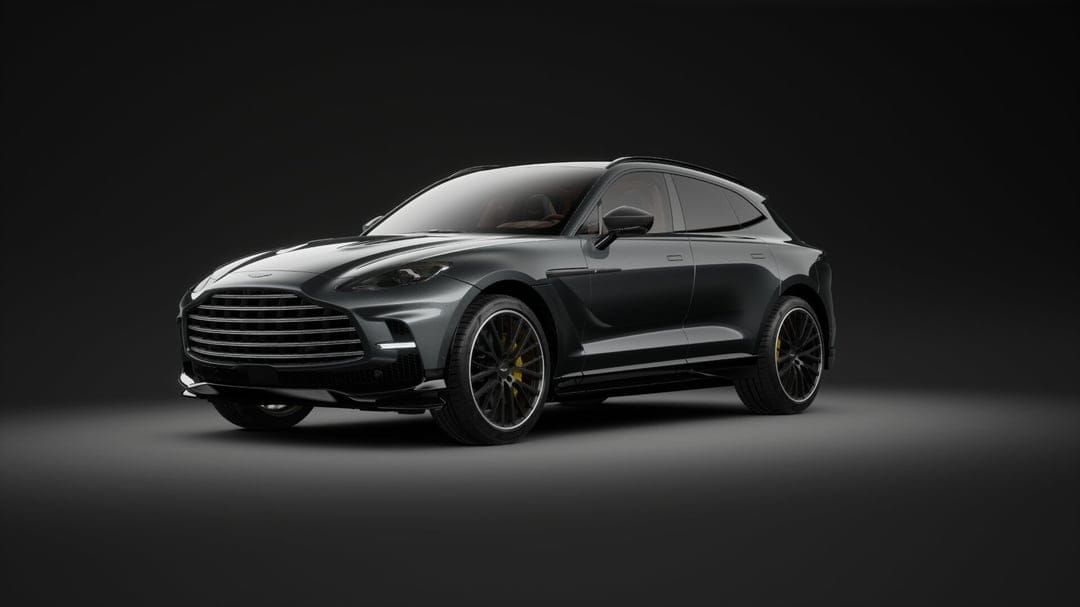 Dark grey Aston Martin DBX luxury SUV with yellow brake calipers in a black studio with professional rim lighting.