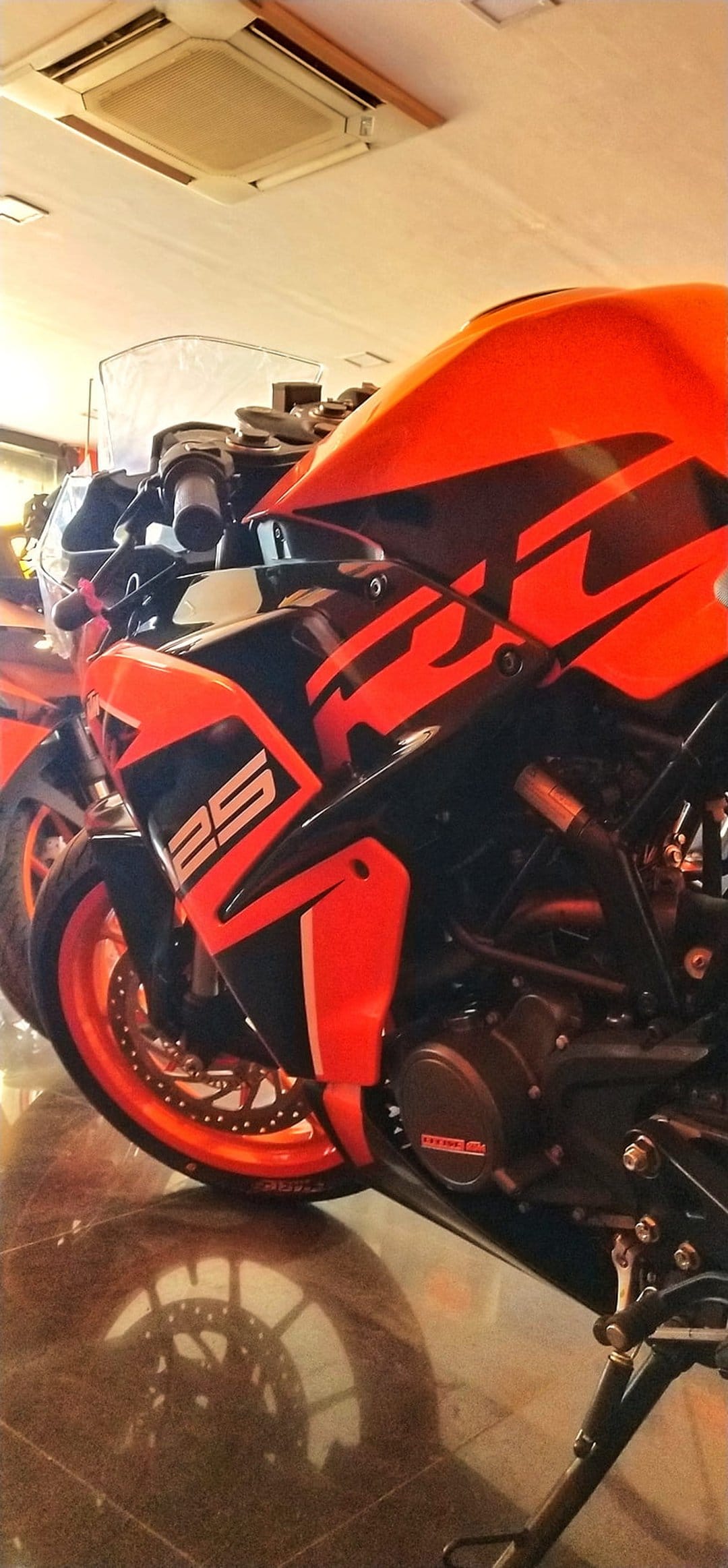 KTM RC 250 sportbike featuring orange fairings, black decals, and racing number twenty-five in a showroom.