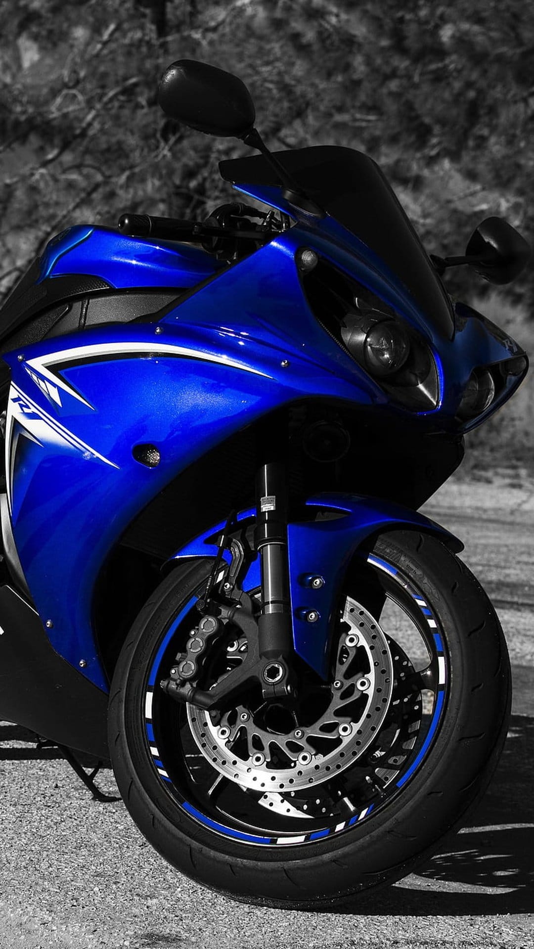 Blue sportbike wheel featuring white racing stripes, a ventilated brake disc, and a sharp motorcycle fairing.