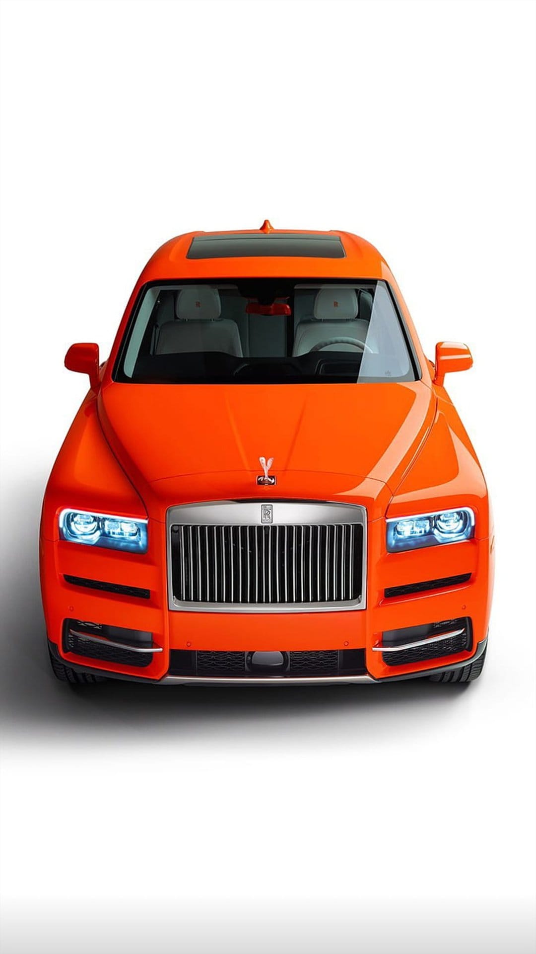 Orange Rolls-Royce Cullinan SUV showing a chrome Pantheon grille, Spirit of Ecstasy, and bright LED headlights.