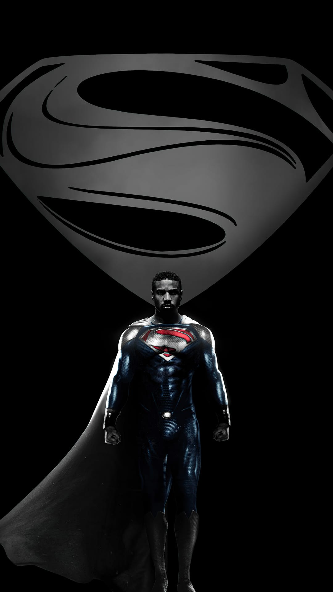 Michael B. Jordan as Superman wears a black textured suit with a red and yellow crest against a dark void.
