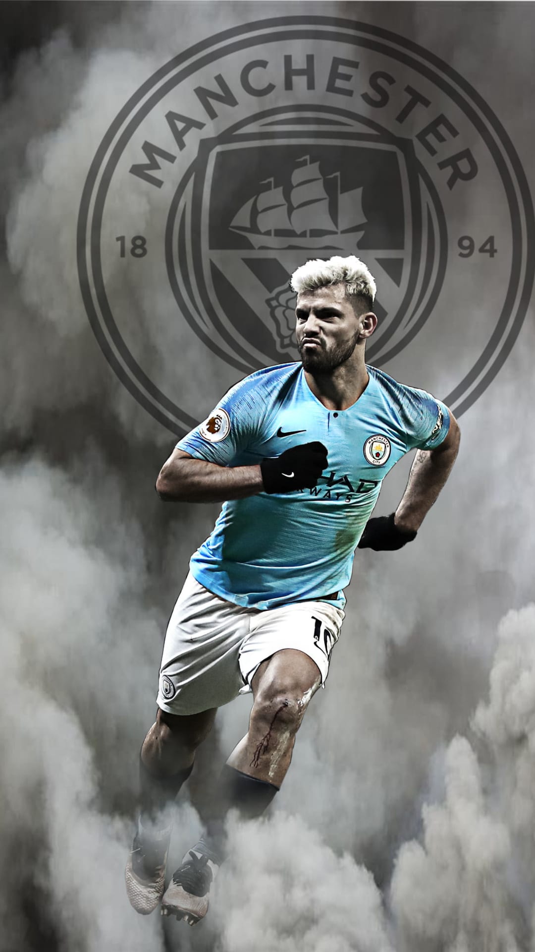 Sergio Aguero runs in a light blue jersey through white smoke against a large grey Manchester City club crest.