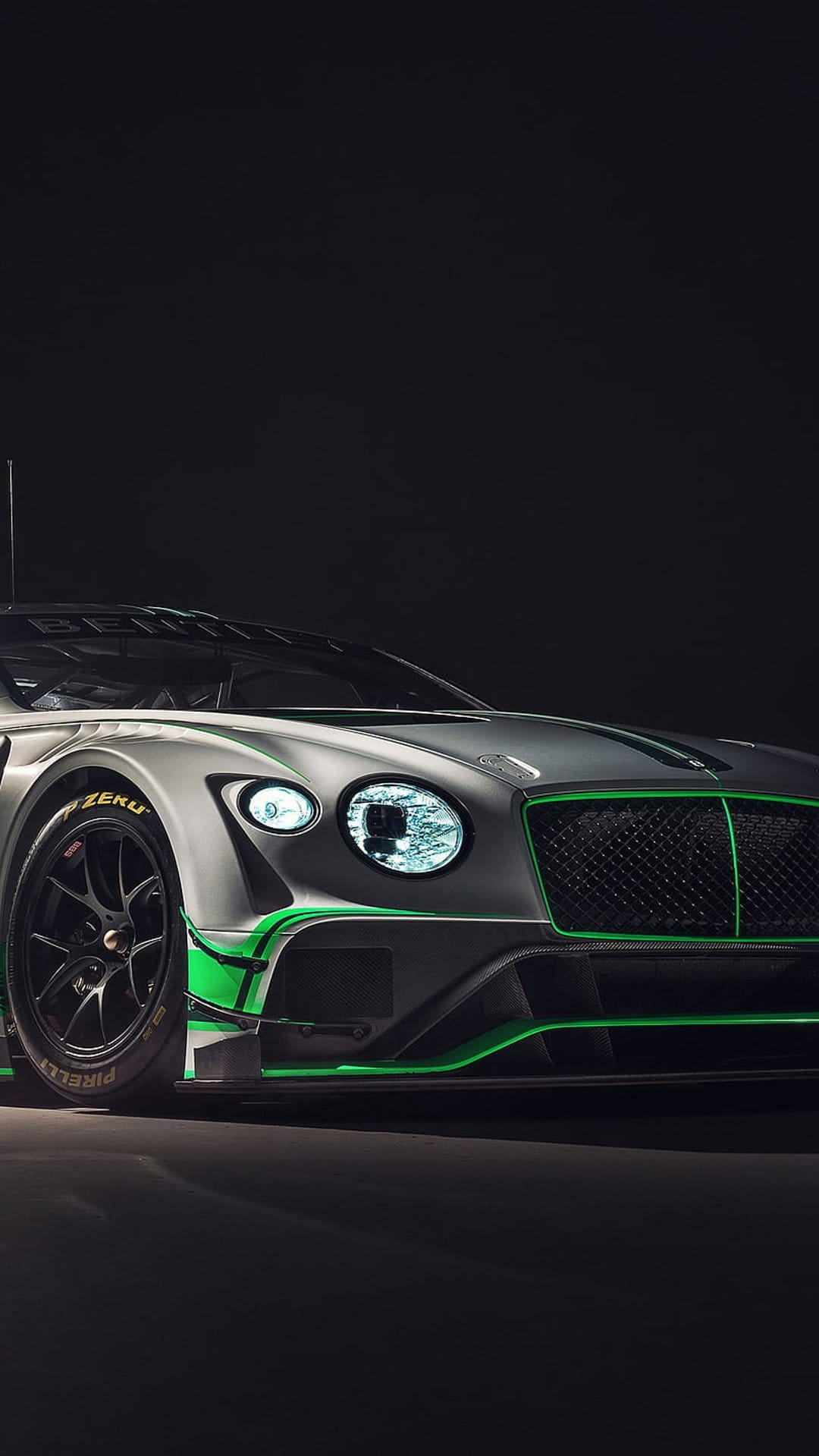 Bentley Continental GT3 race car features silver bodywork, lime green accents, and illuminated LED headlights.