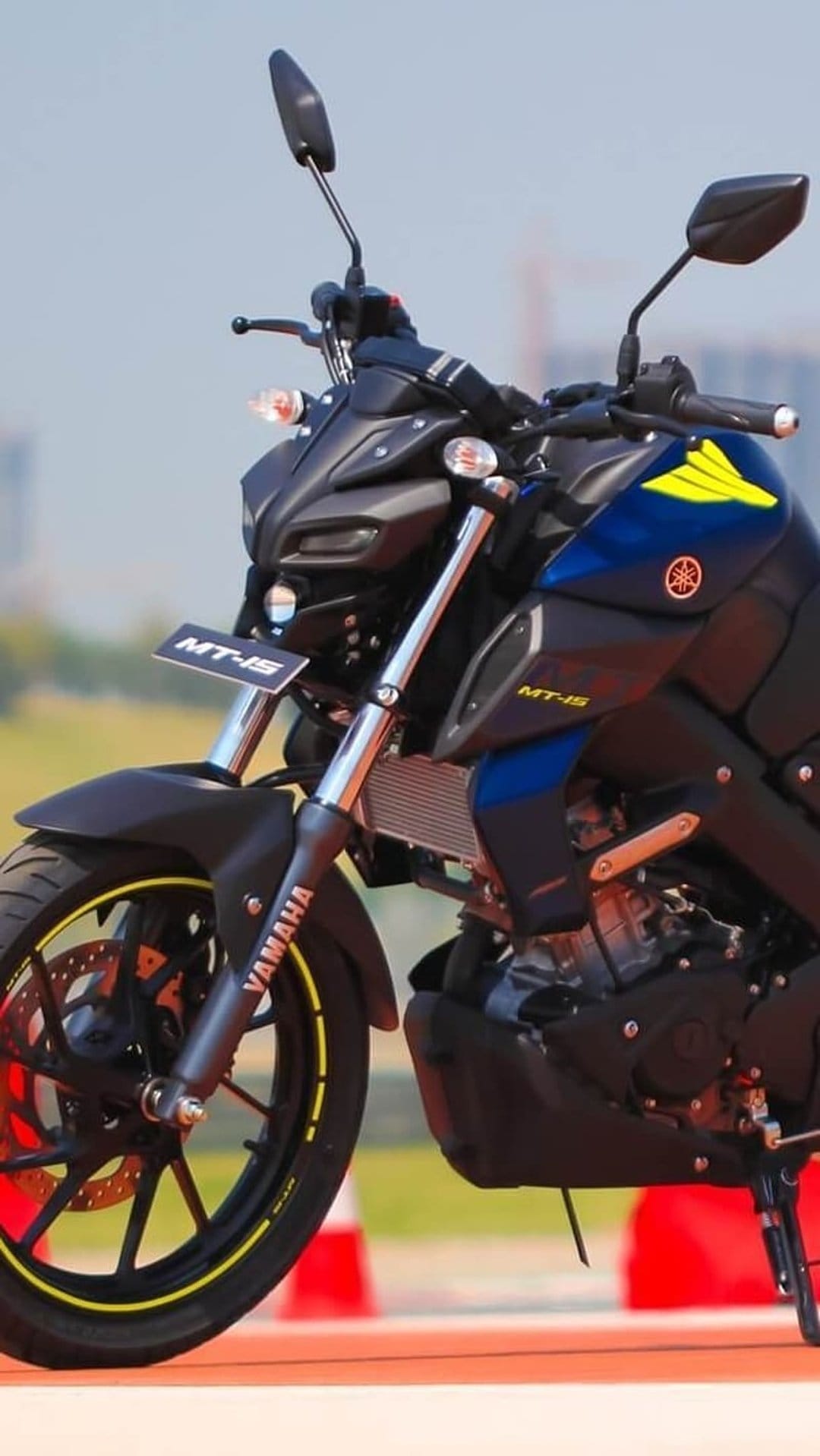 Yamaha MT-15 motorcycle front tire and gold inverted forks with cyan graphics on a dark street bike frame.