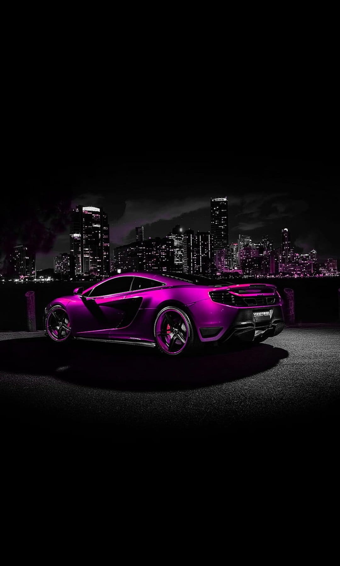 Purple McLaren sports car parked on a road with illuminated city skyscrapers and a dark night sky background.