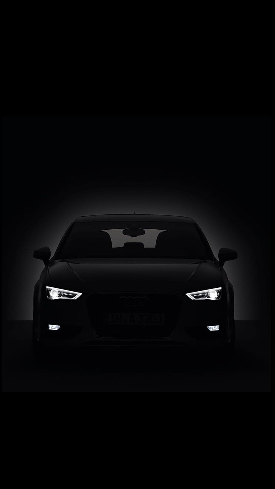 Audi sedan silhouette with glowing white LED headlights and a bat-shaped reflection on the dark windshield glass.