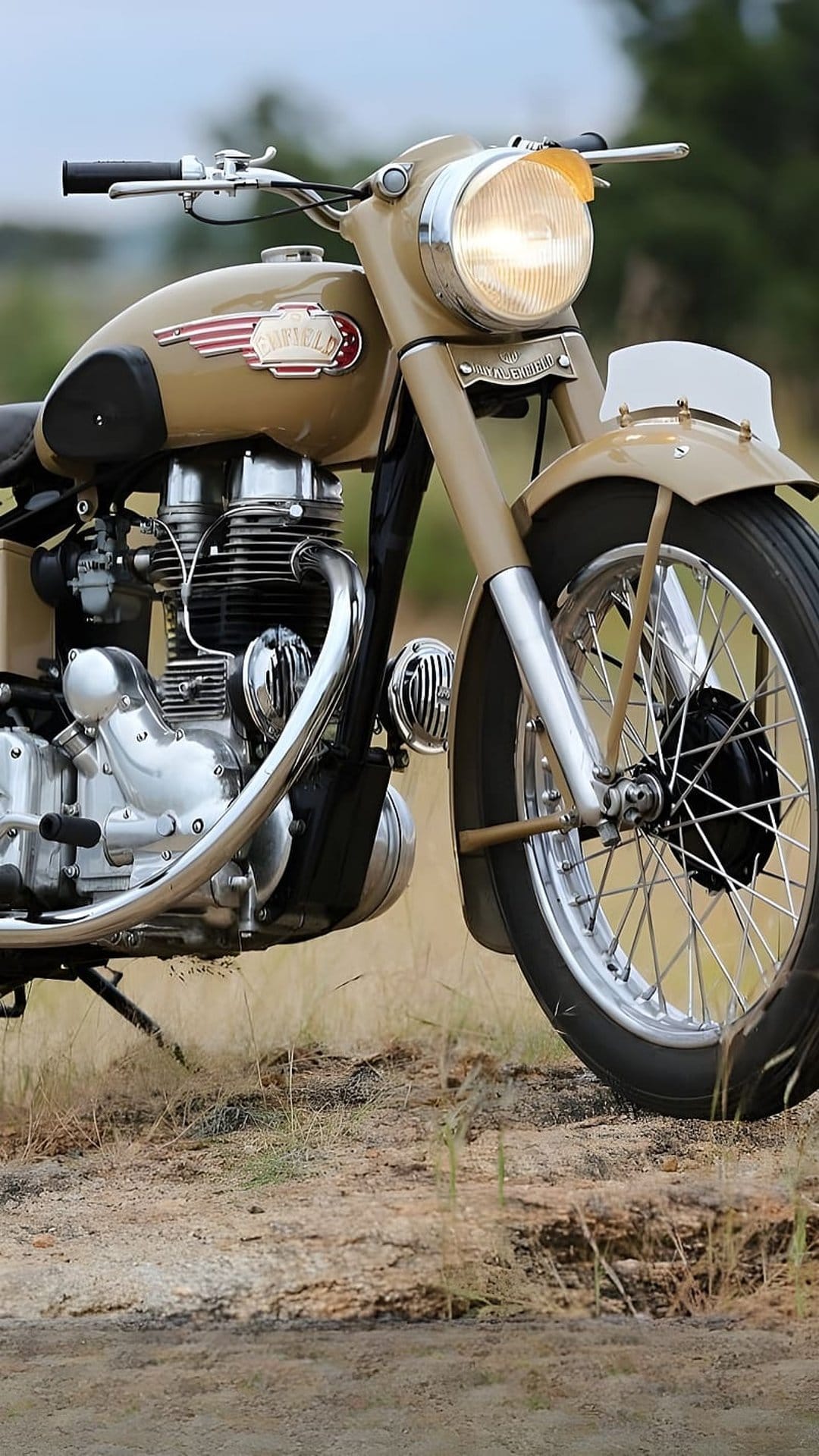 Vintage Royal Enfield motorcycle in sandy beige with chrome exhaust parked on dry, grassy desert terrain.