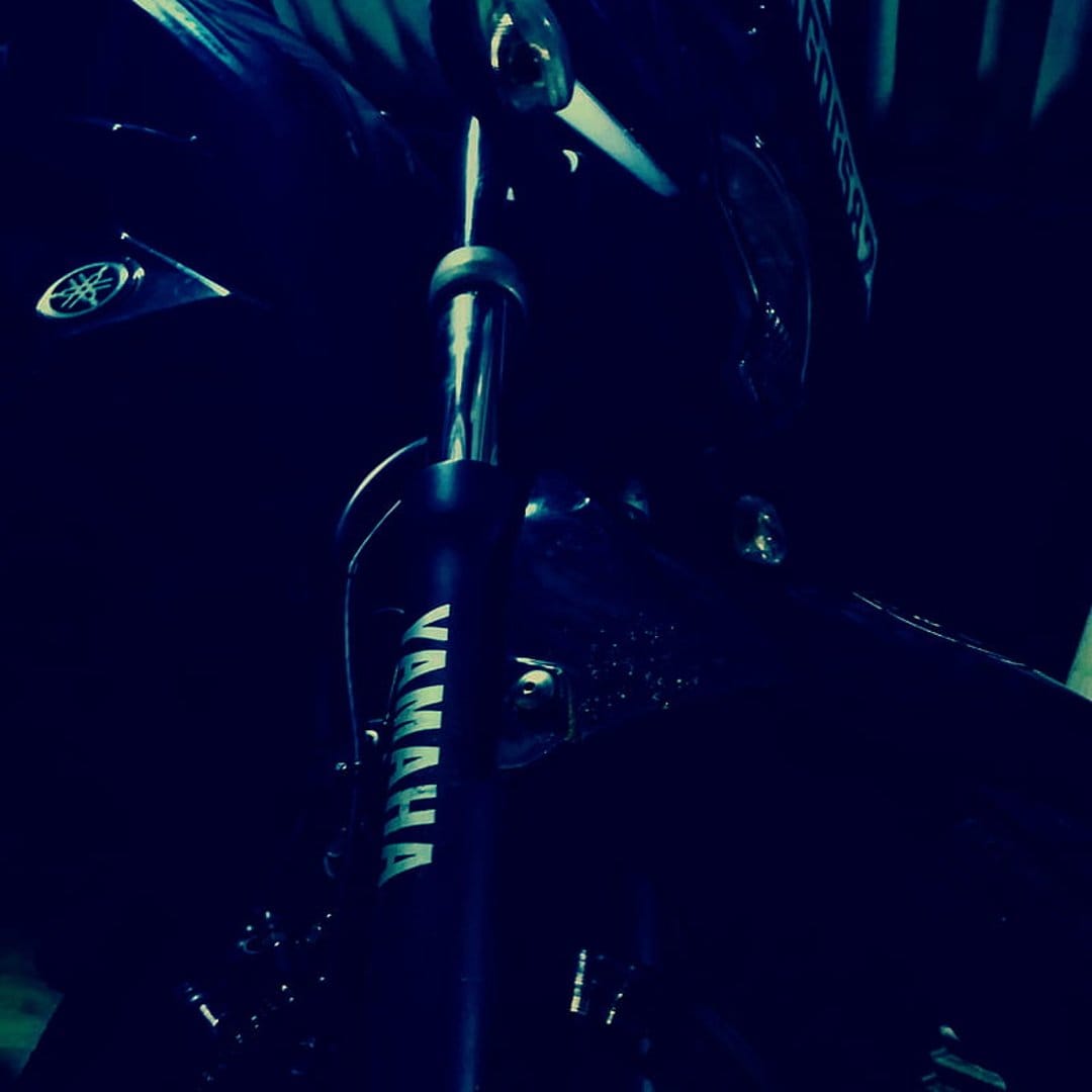 Yamaha motorcycle front fork suspension with a visible logo on a dark, moody background highlighting mechanics.