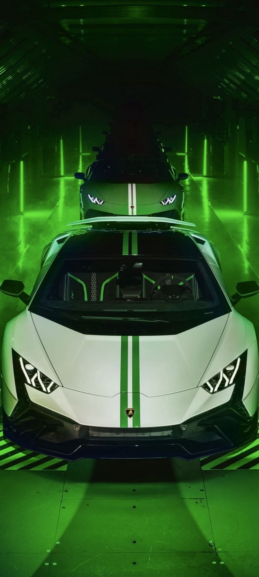 Two white Lamborghini supercars with green racing stripes parked inside a futuristic dark tunnel with neon lights.