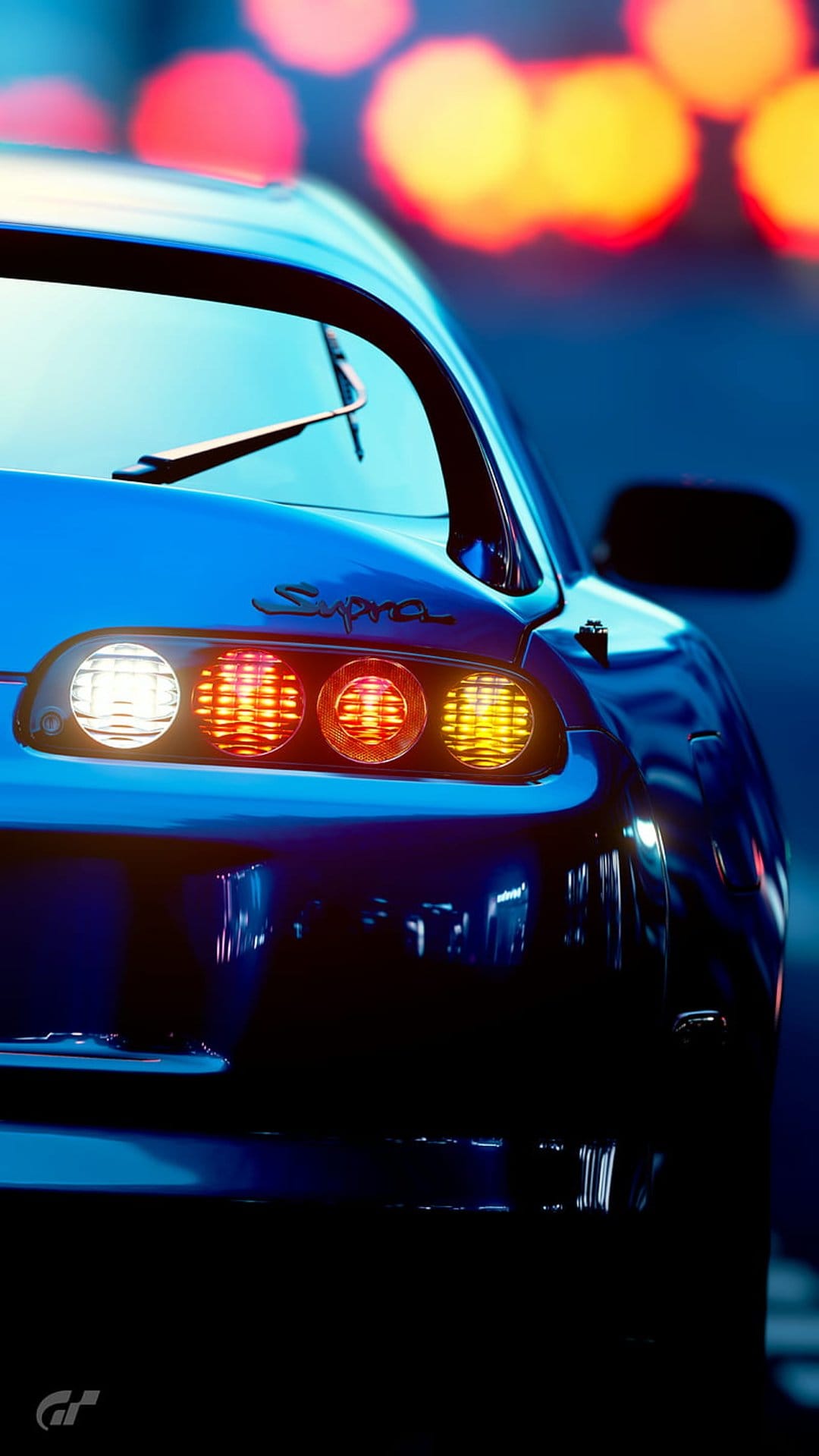 Toyota Supra circular taillights glowing with red and orange light against a dark background with yellow bokeh.