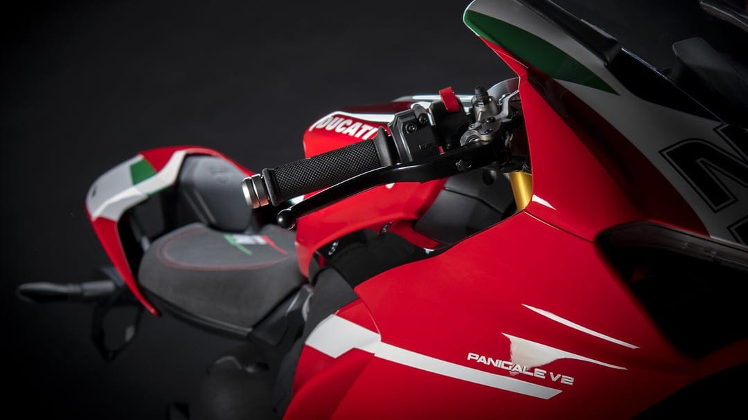 Red Ducati Panigale V2 motorcycle handlebar and fairing with Italian flag colors on a black background.