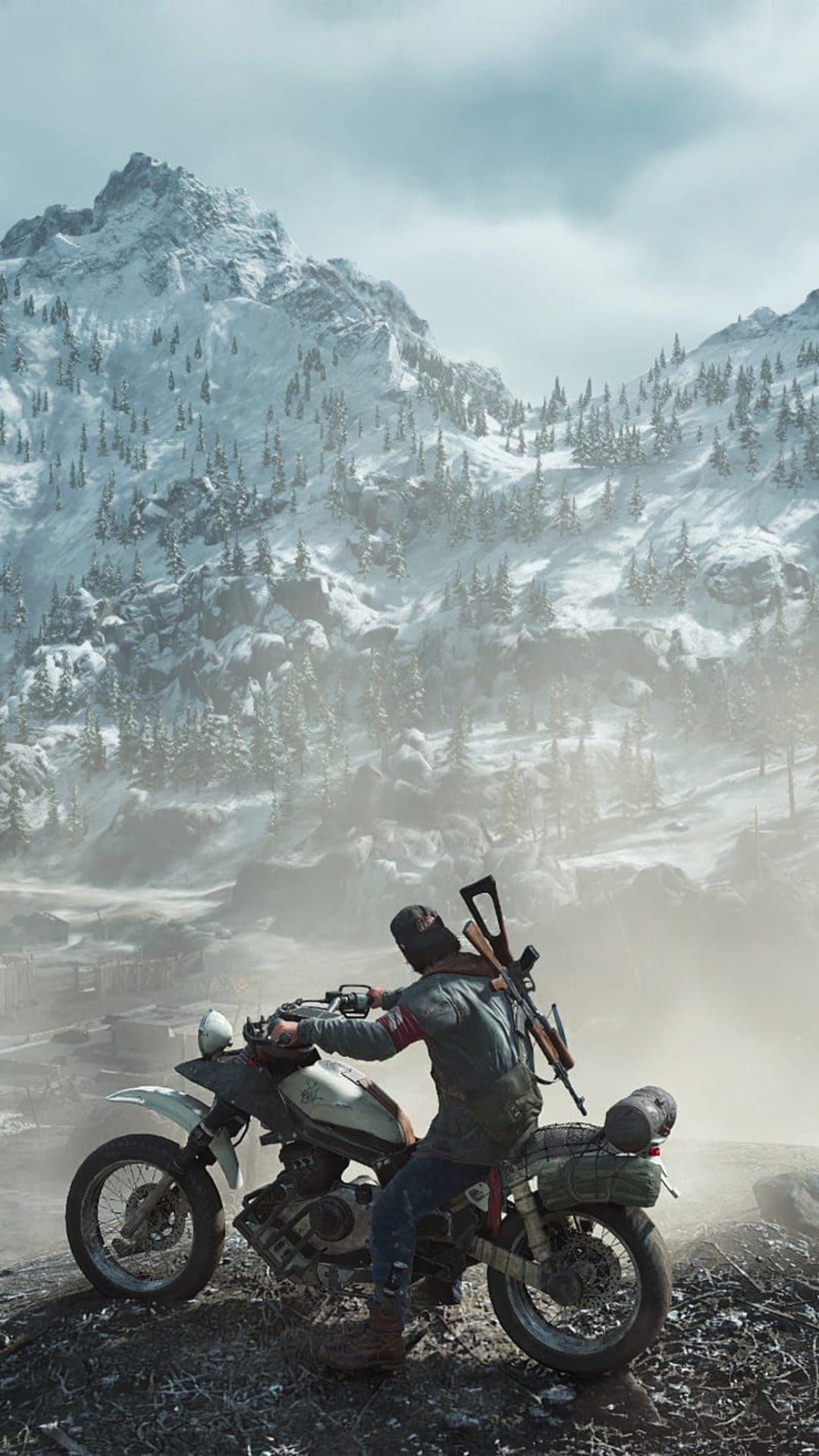 Biker with a rifle over his shoulder sits on a motorcycle overlooking snowy mountain peaks shrouded in thick mist.