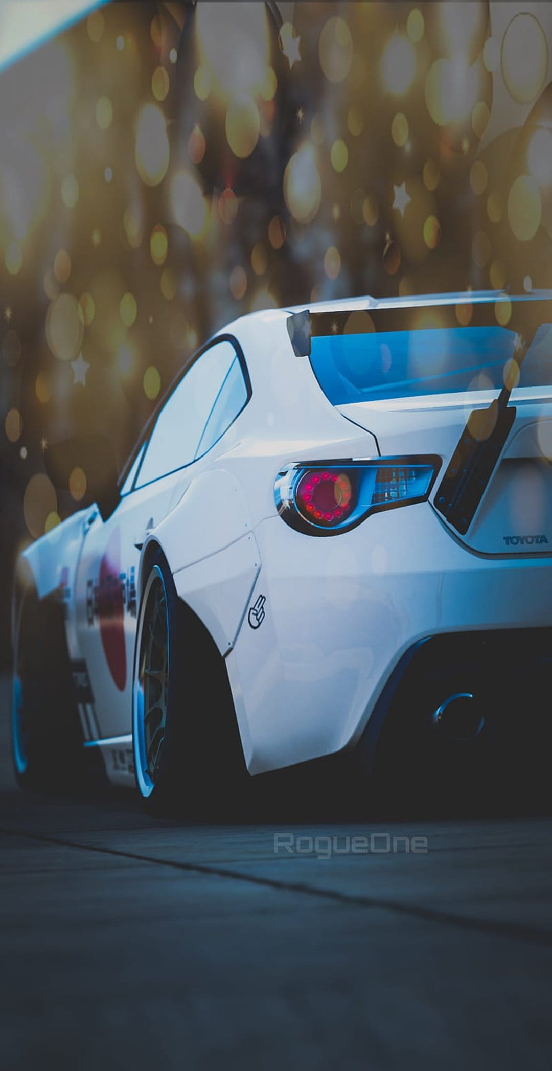 White Toyota GT86 with widebody kit and rear spoiler parked at night against blurred golden bokeh lights.