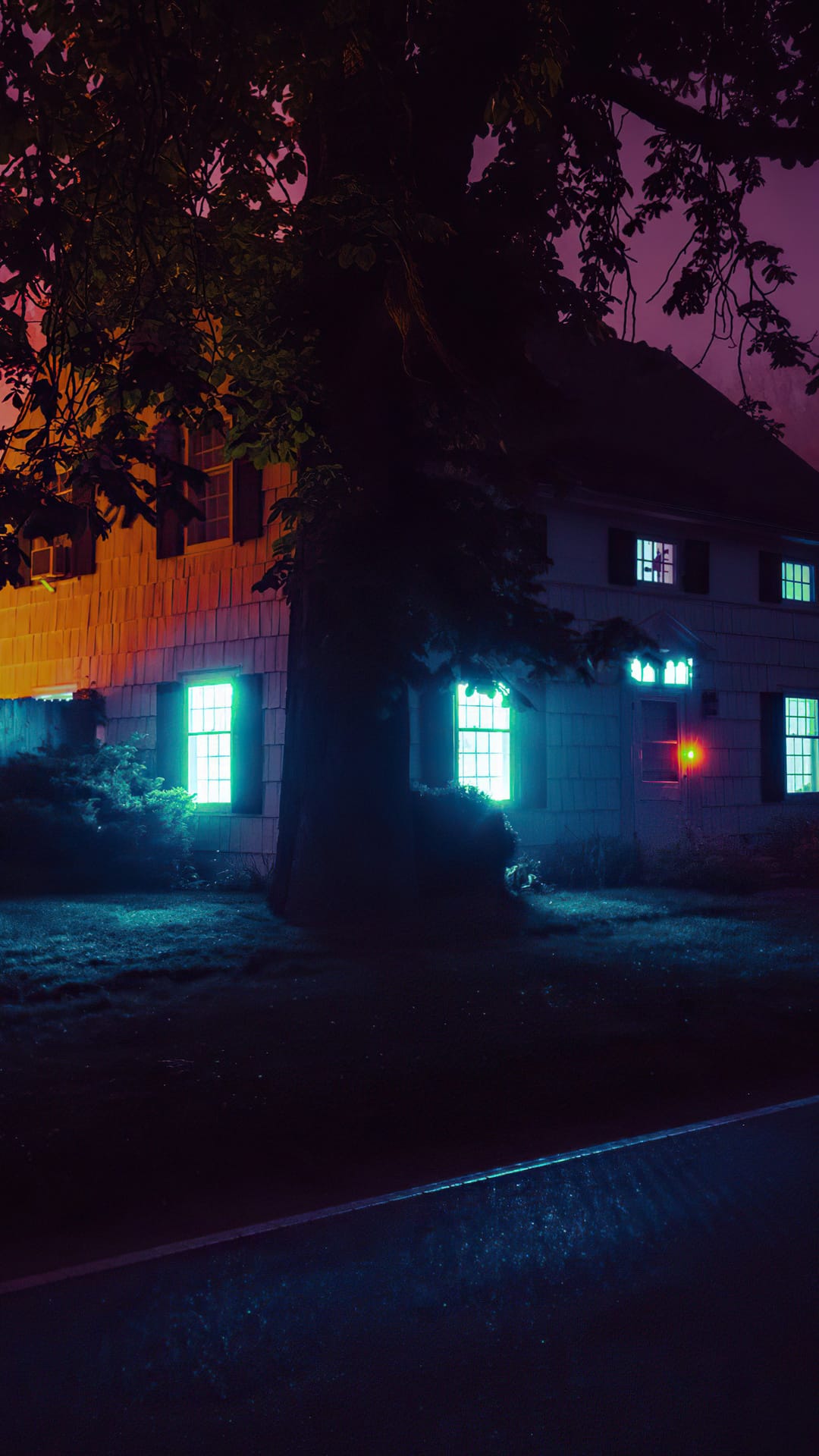 Suburban house at night with windows glowing in neon green and blue lights behind a dark tree silhouette.