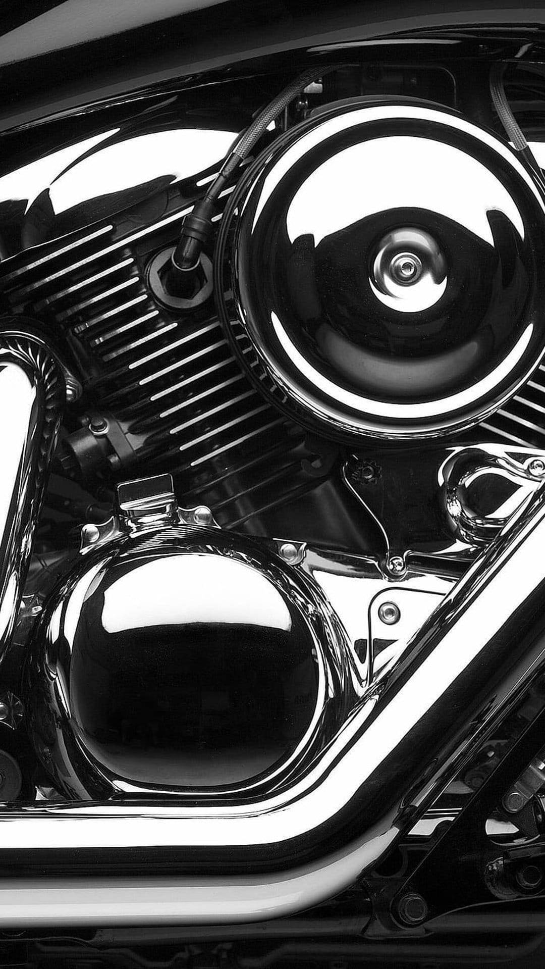 Chrome motorcycle engine with a round air cleaner and dual exhaust pipes featuring polished metallic surfaces.