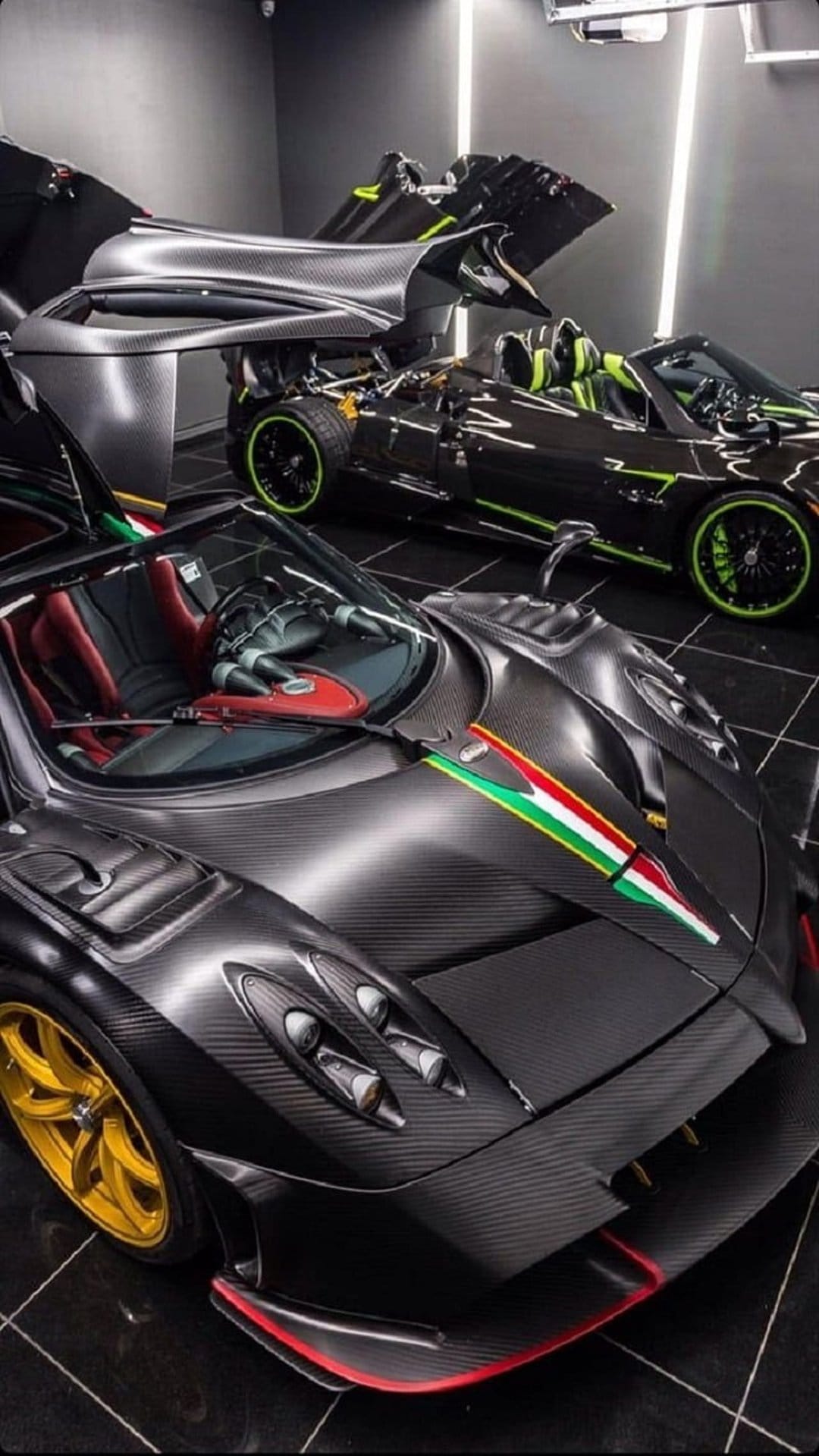 Pagani hypercars with exposed carbon fiber and green accents parked in a minimalist luxury garage display.