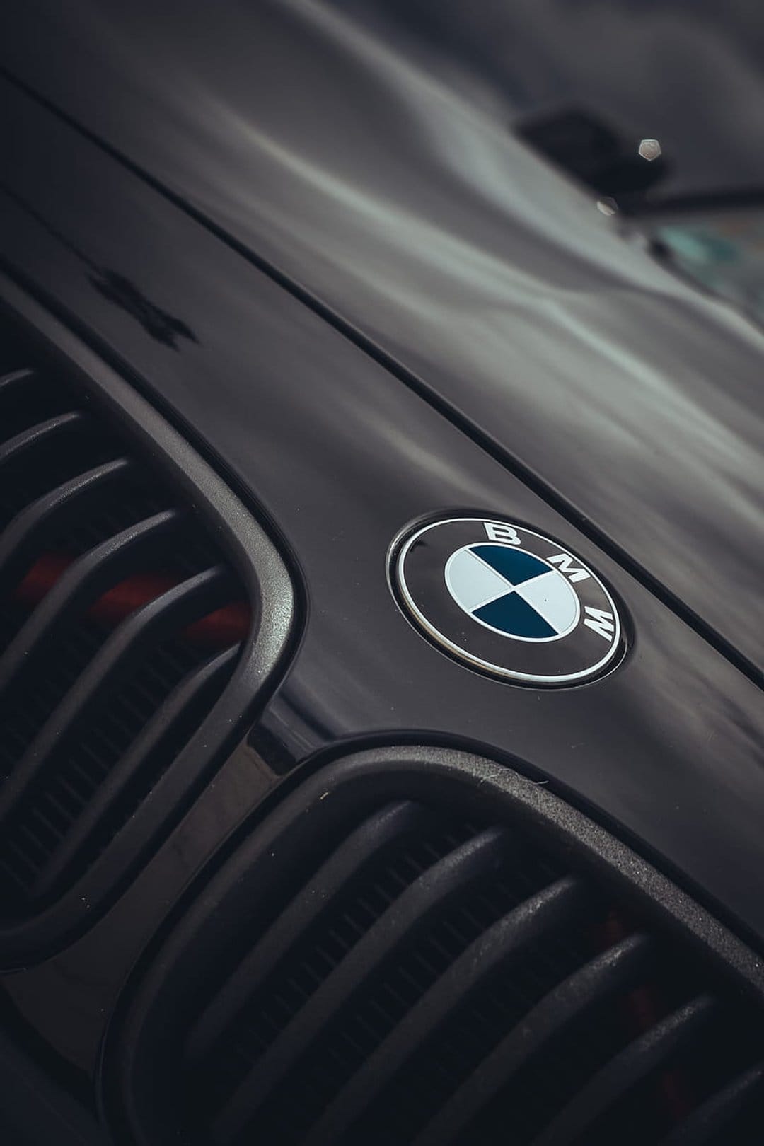 BMW circular emblem and vertical black kidney grille on a luxury sports car with dramatic shadow lighting.