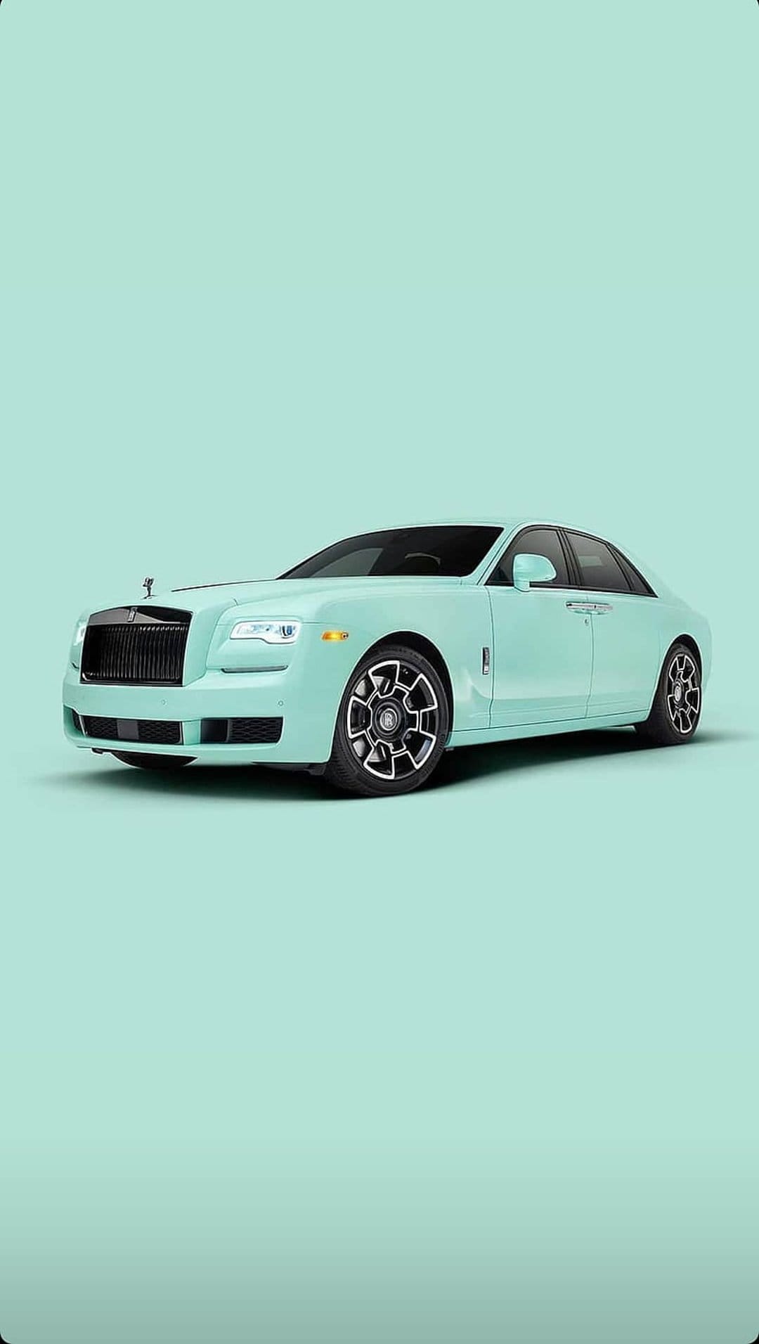 Rolls-Royce Ghost in mint green with a chrome grille and alloy wheels against a pastel minimalist background.